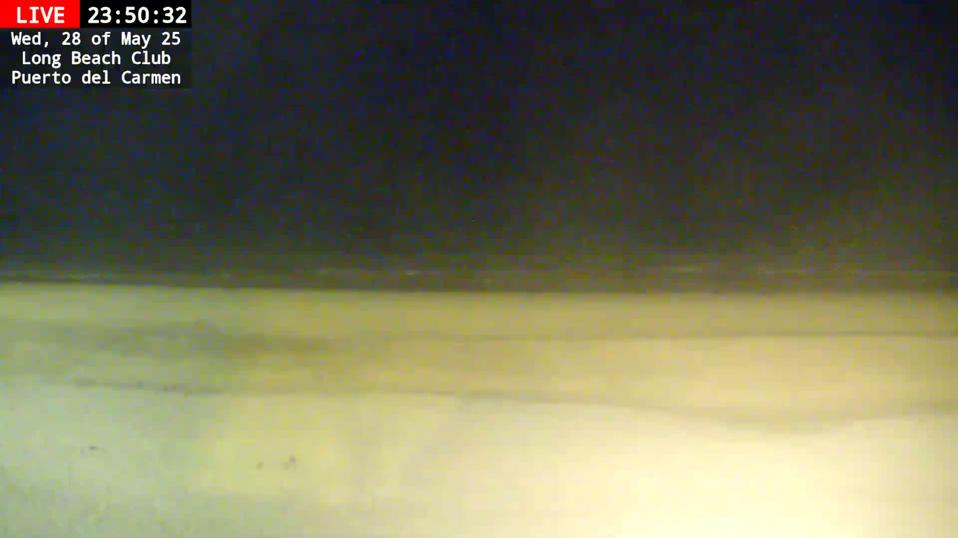 A nighttime view shows a dark sky over a light-colored sandy beach.