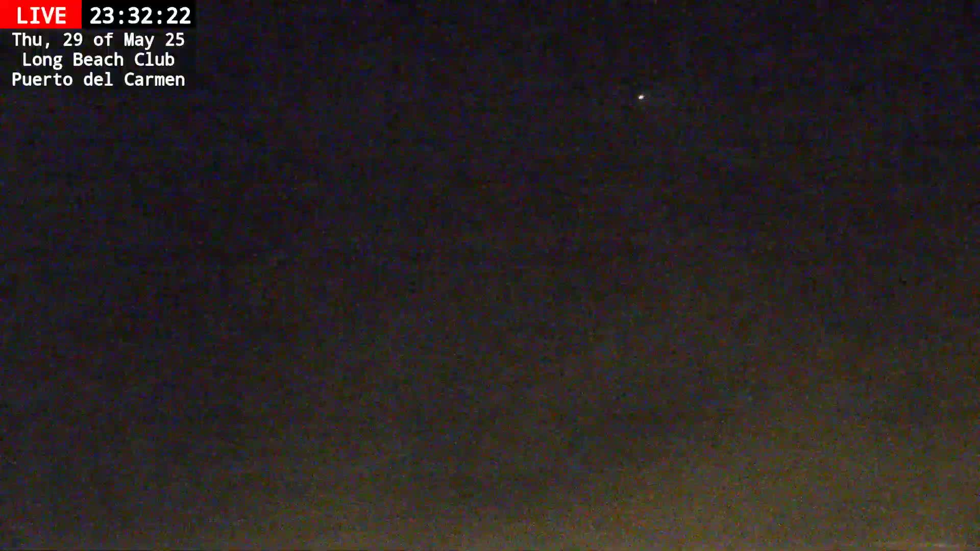 A nighttime, dark outdoor scene shows a mostly clear sky with a single, faint light visible.