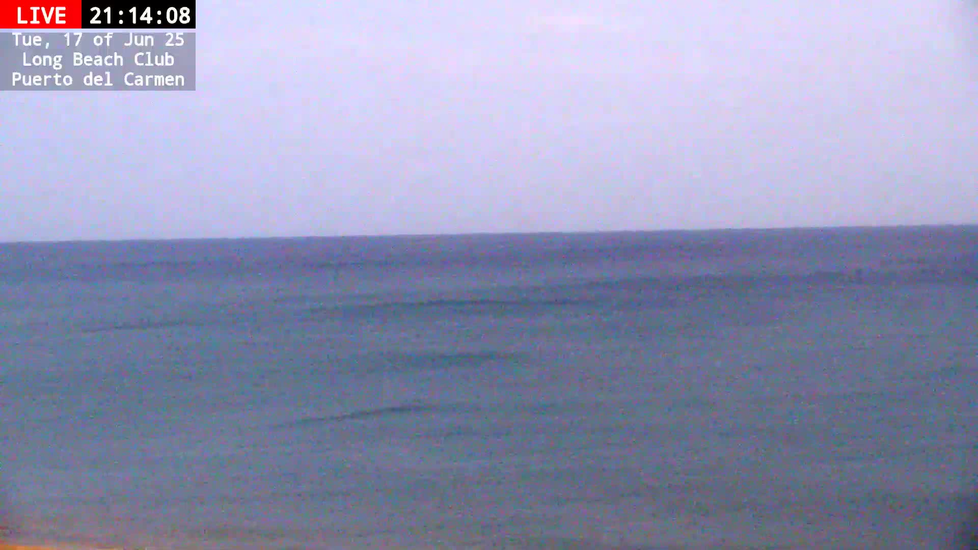 A calm, gray-sky day shows a gently waving ocean extending to the horizon.