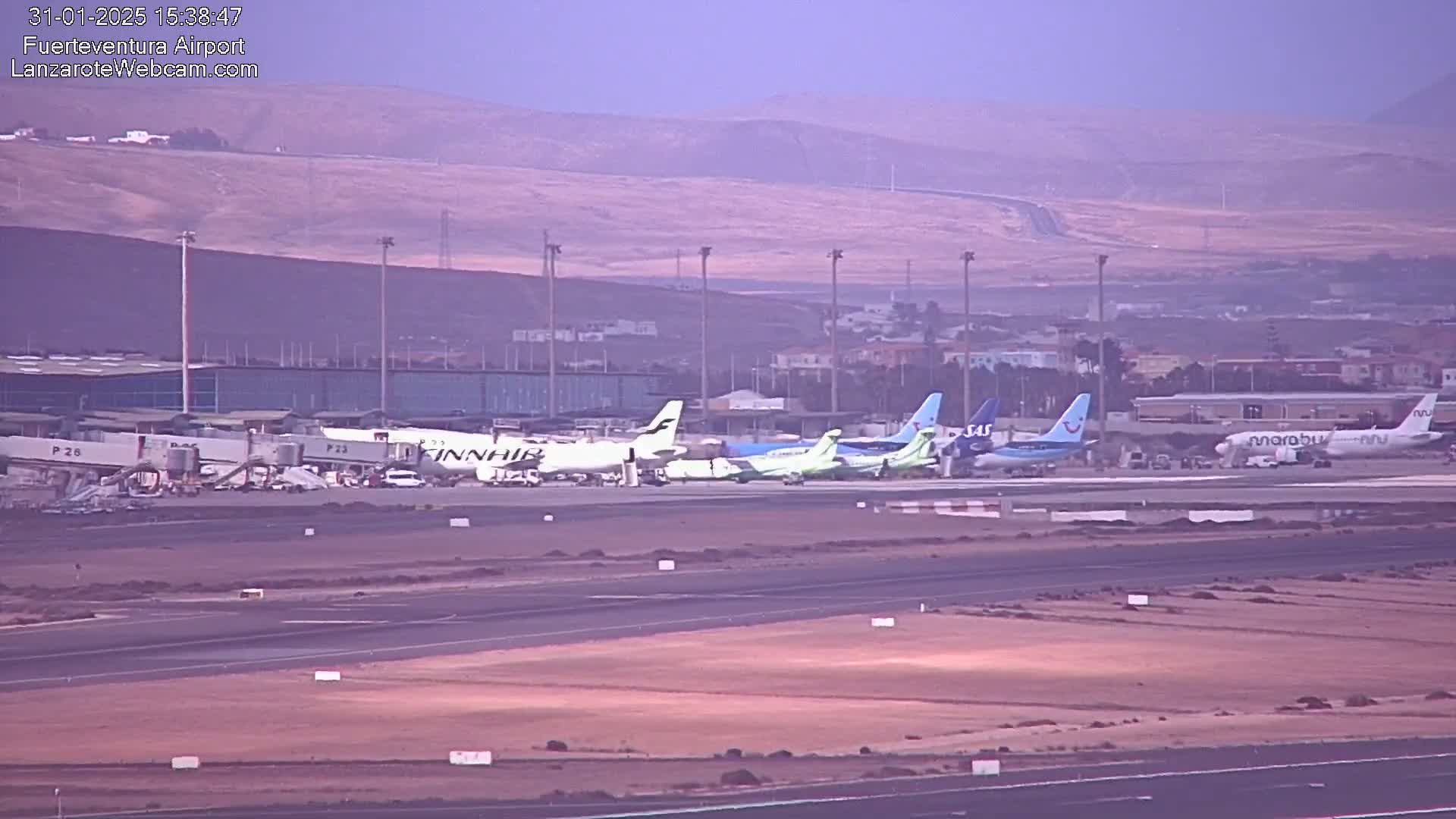 Several airplanes are parked at an airport on a hazy day.