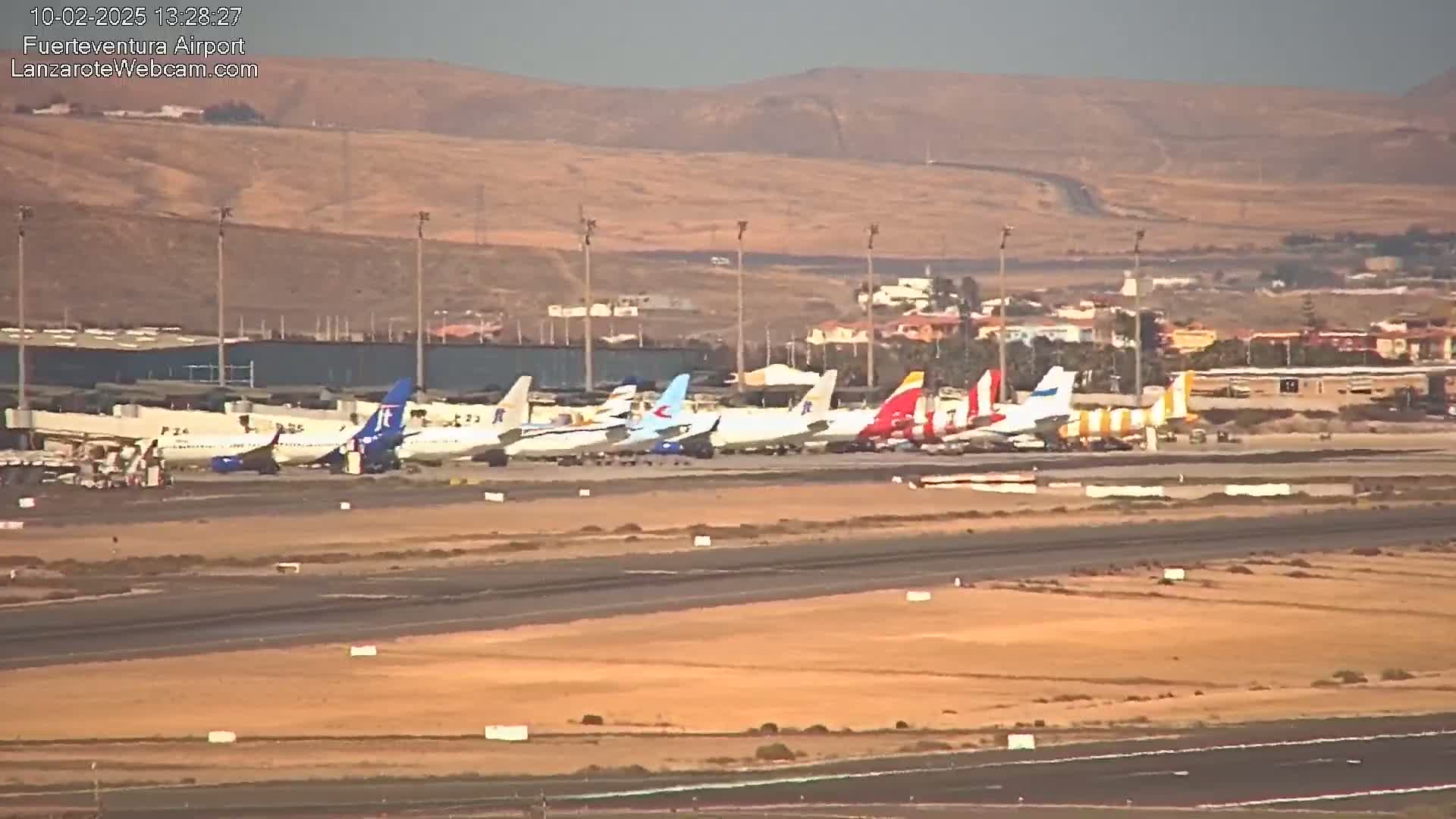 Several airplanes are parked on a tarmac at an airport, with hazy or dusty conditions visible in the background.