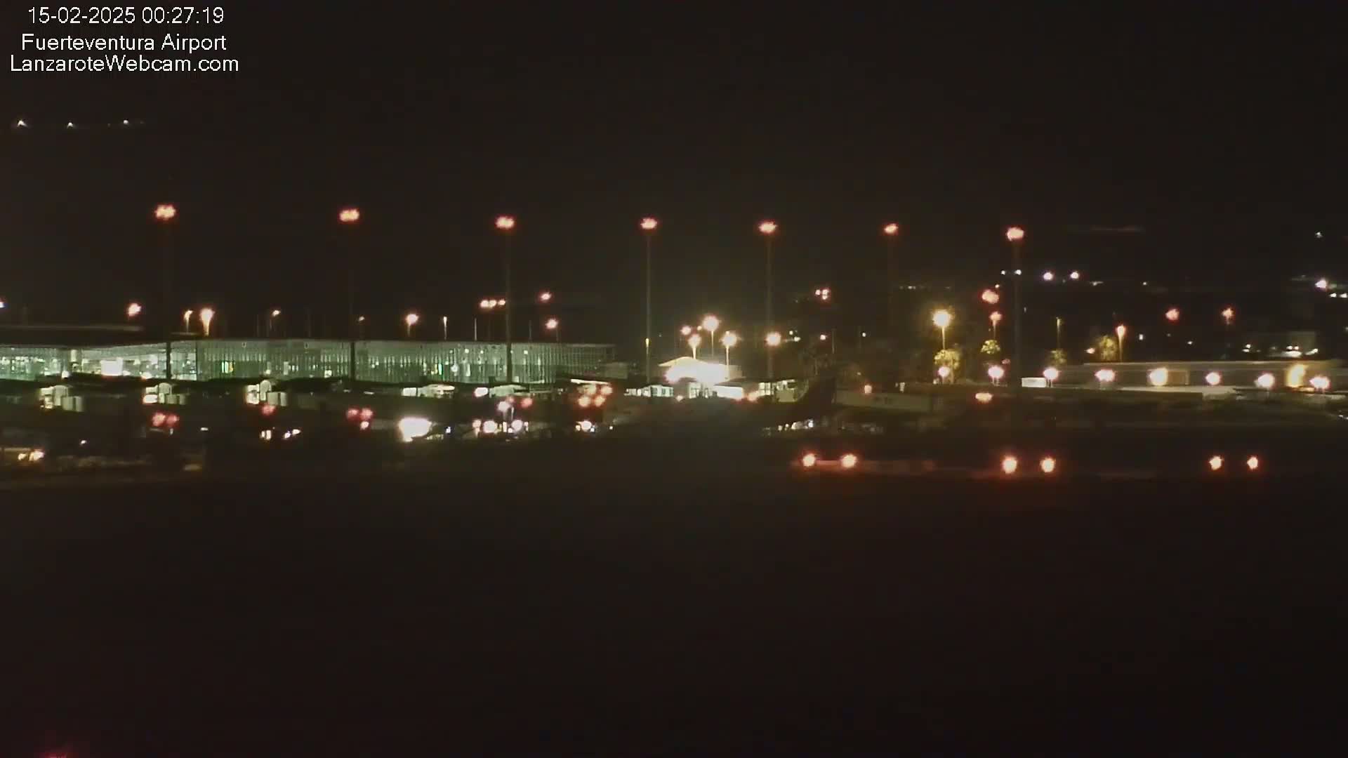 A nighttime view of an airport with numerous lights illuminating the tarmac and buildings.