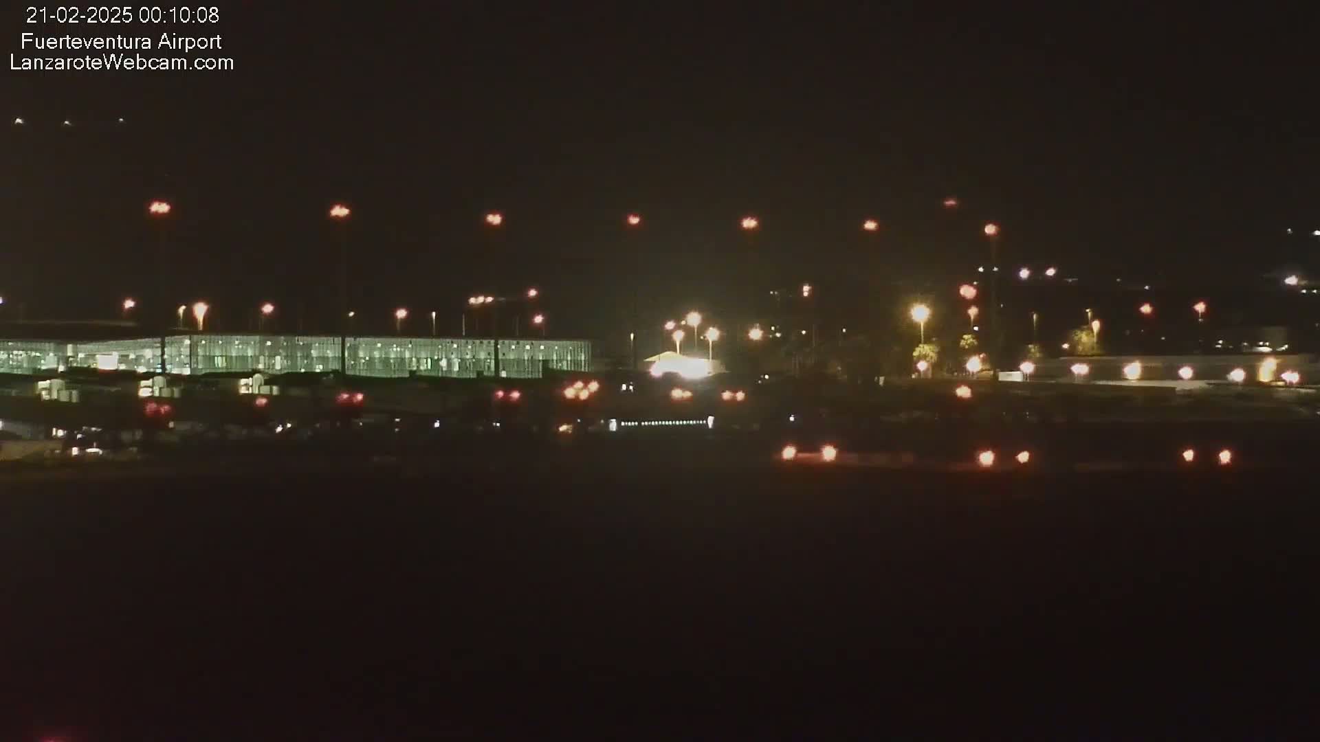 A brightly lit airport terminal and surrounding area at night, under a clear, dark sky.