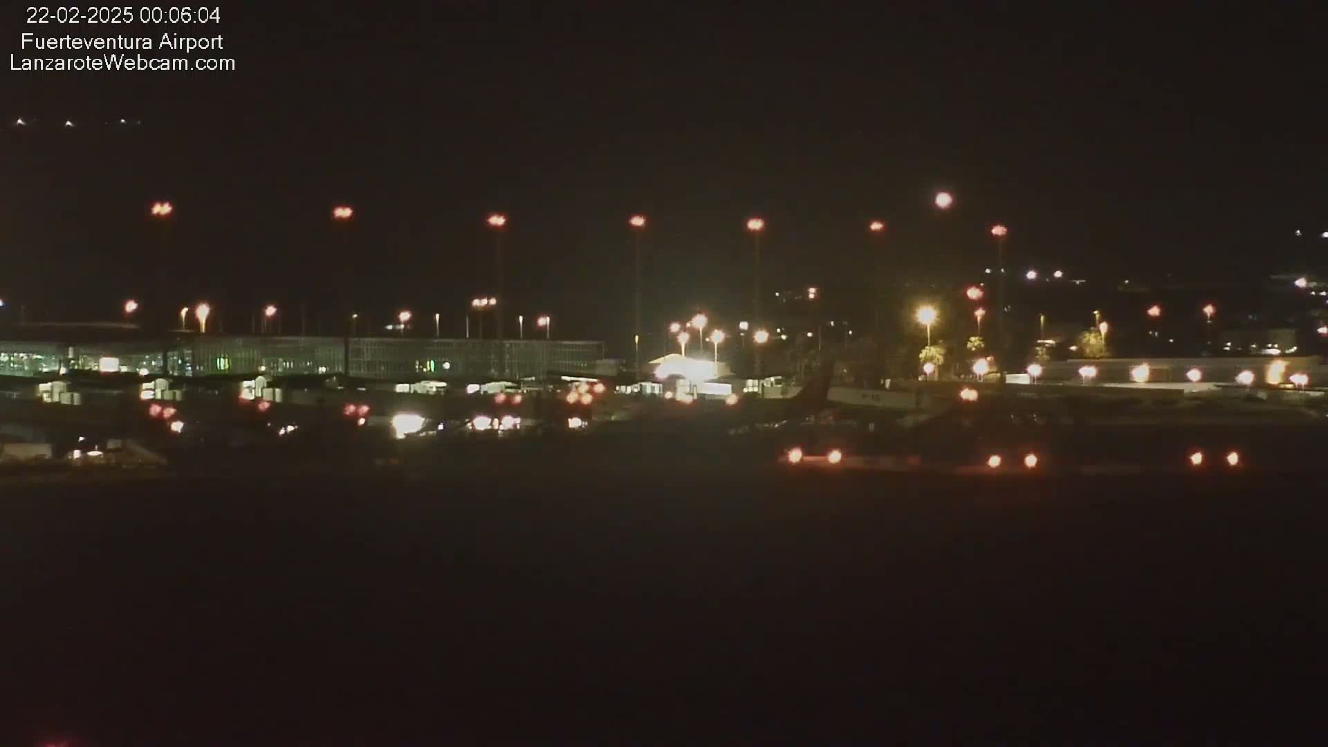 A nighttime long shot of an airport with numerous lights illuminating the tarmac and buildings.
