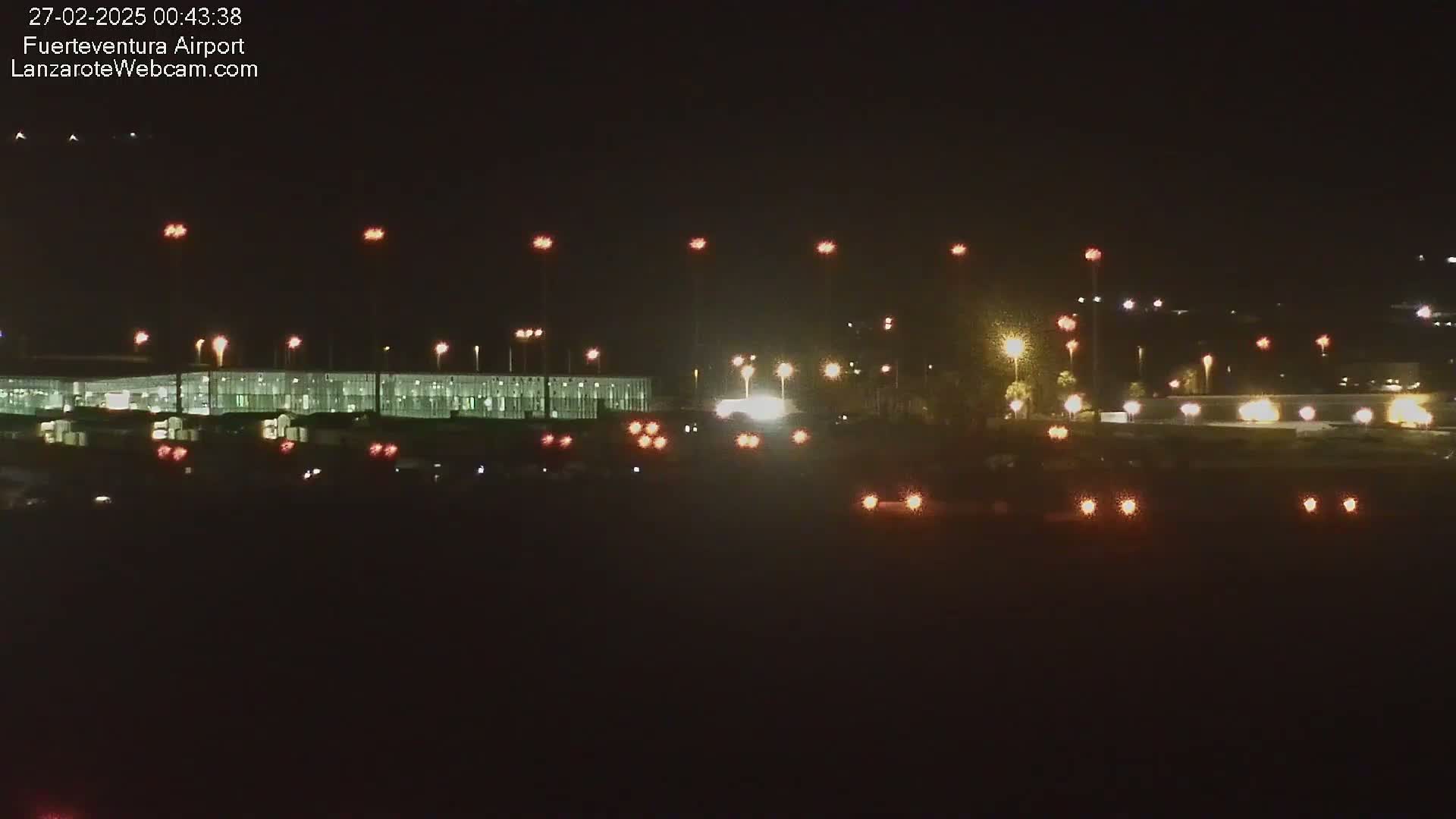 A nighttime long shot of an airport terminal building and its surrounding area, illuminated by numerous lights.