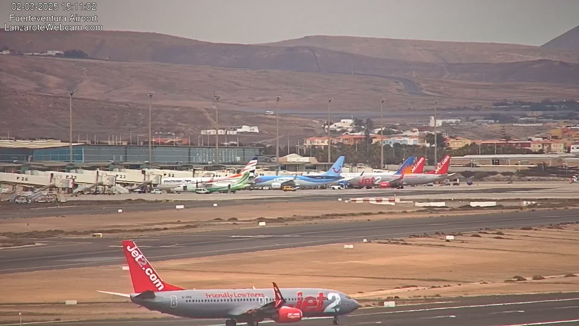 Several airplanes are parked at an airport on a hazy day, with one airplane taxiing on the runway.