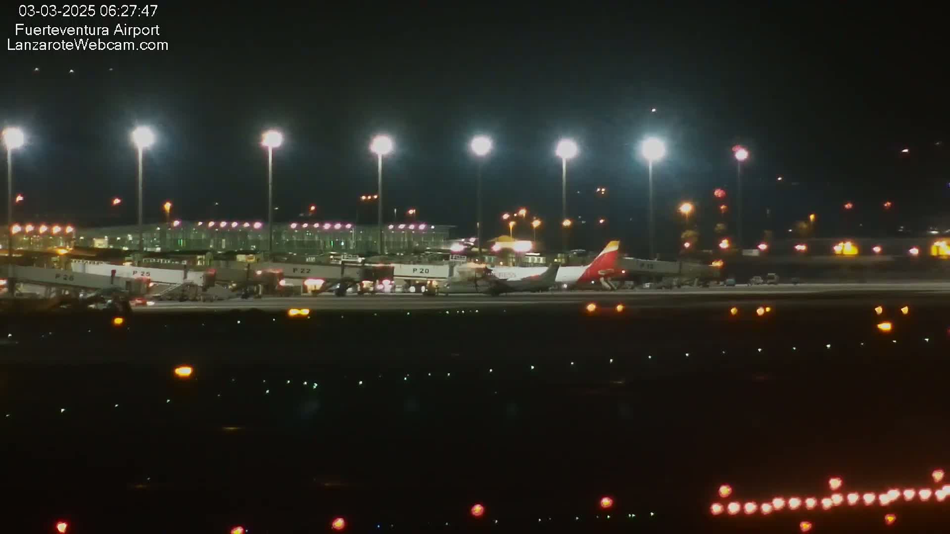 A plane is parked at an airport at night under bright lights.
