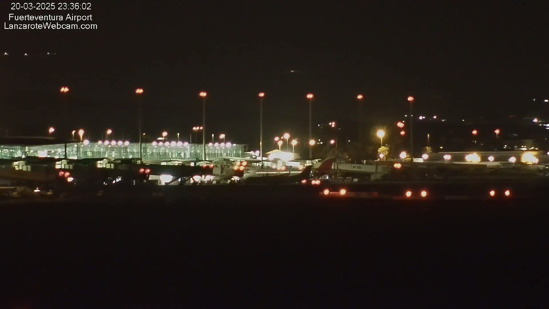 At night, brightly lit airplanes and airport terminals are visible under a clear, dark sky.
