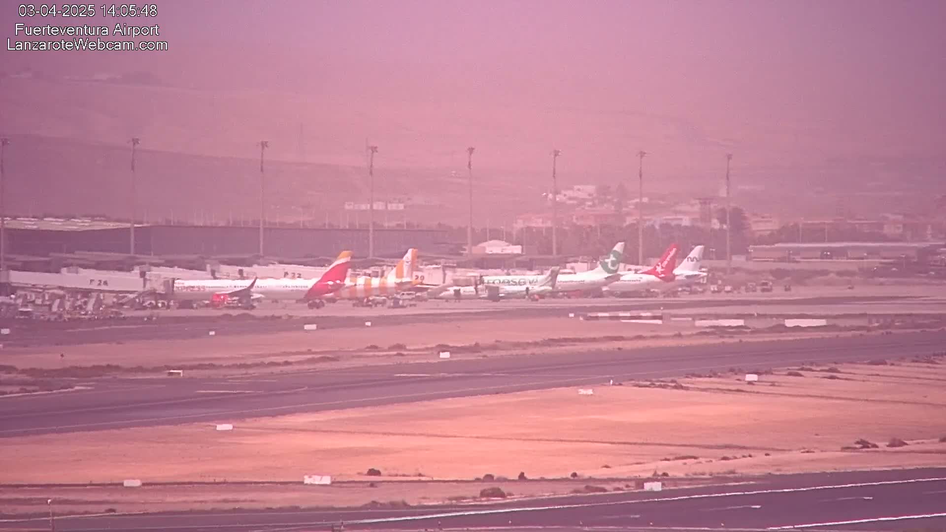 Several airplanes are parked at an airport in hazy conditions.