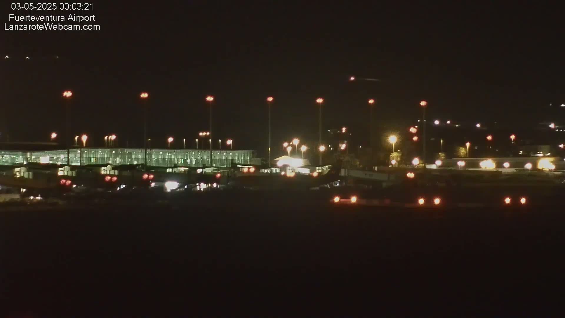 A brightly lit airport terminal and surrounding area at night, with numerous lights illuminating the tarmac and buildings.