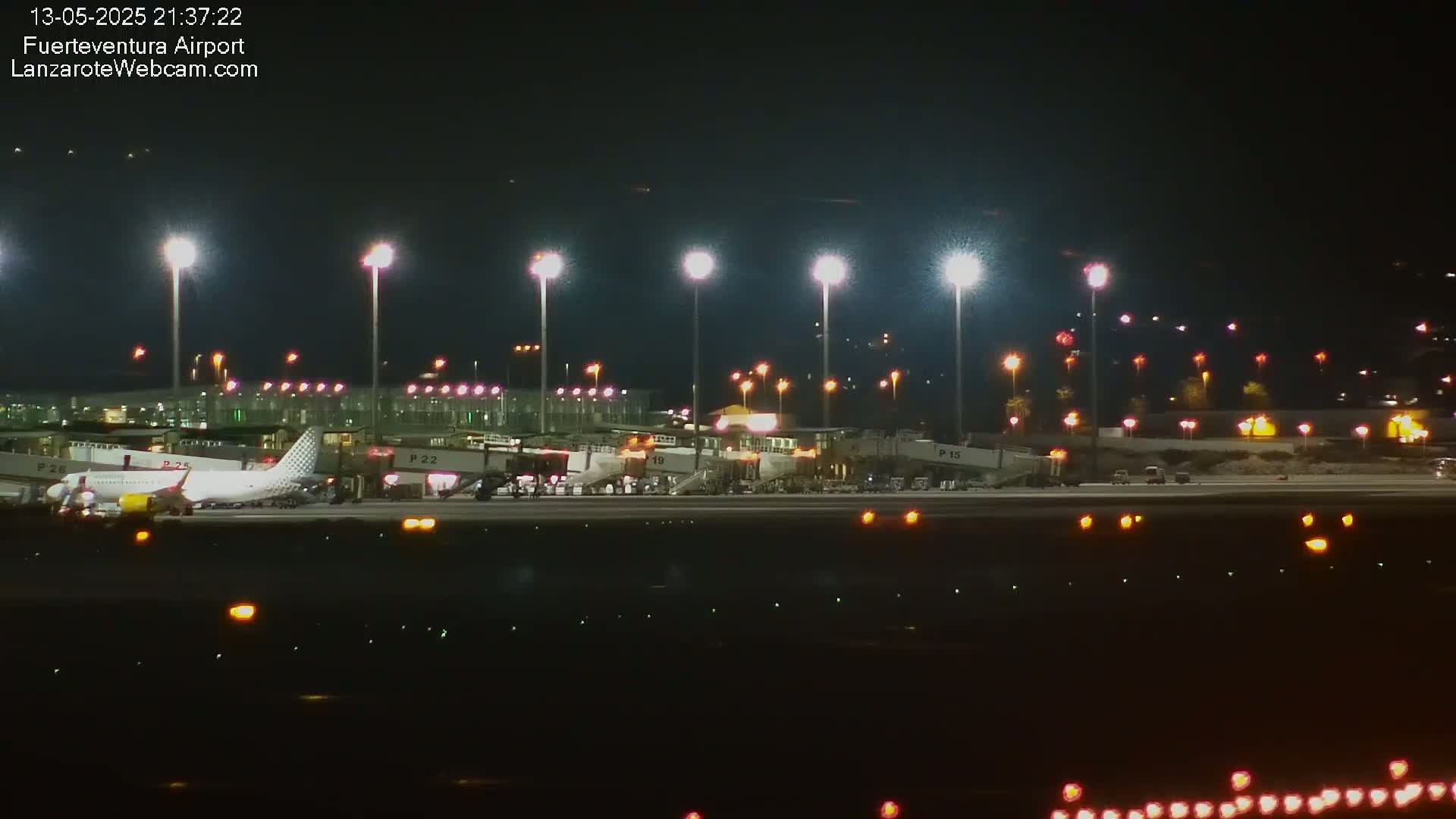 A plane is parked at a brightly lit airport at night.