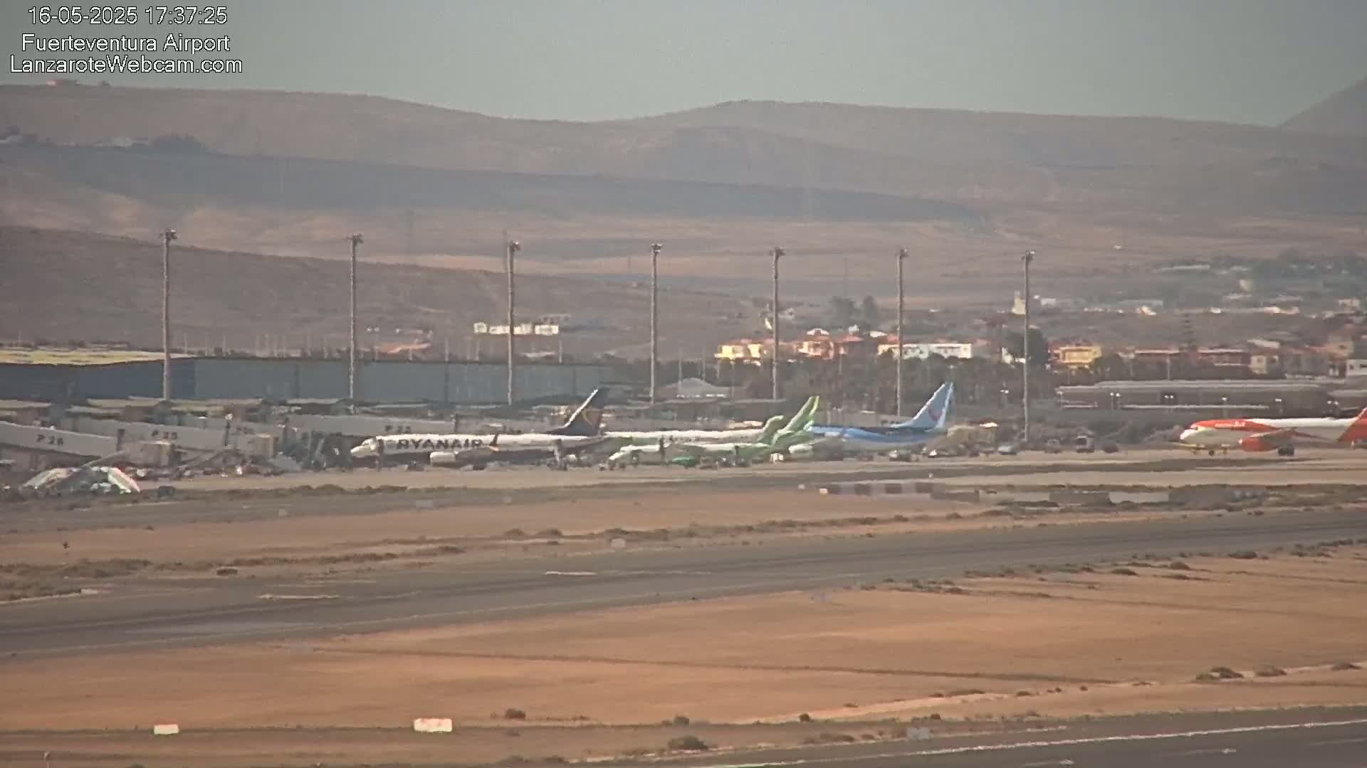 Several airplanes are parked on a tarmac at an airport on a hazy day.