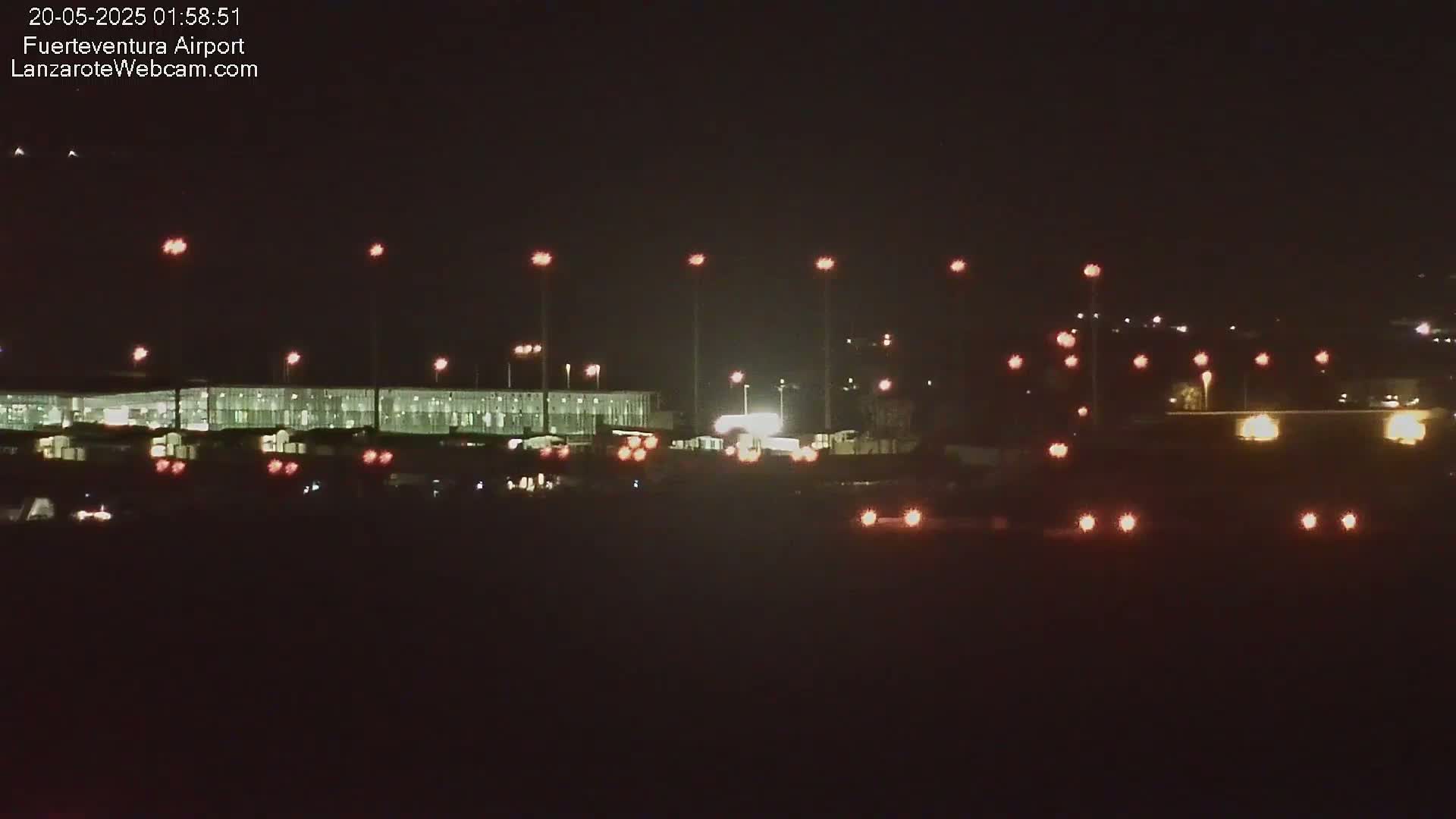 A brightly lit airport terminal at night is visible under a dark, clear sky.