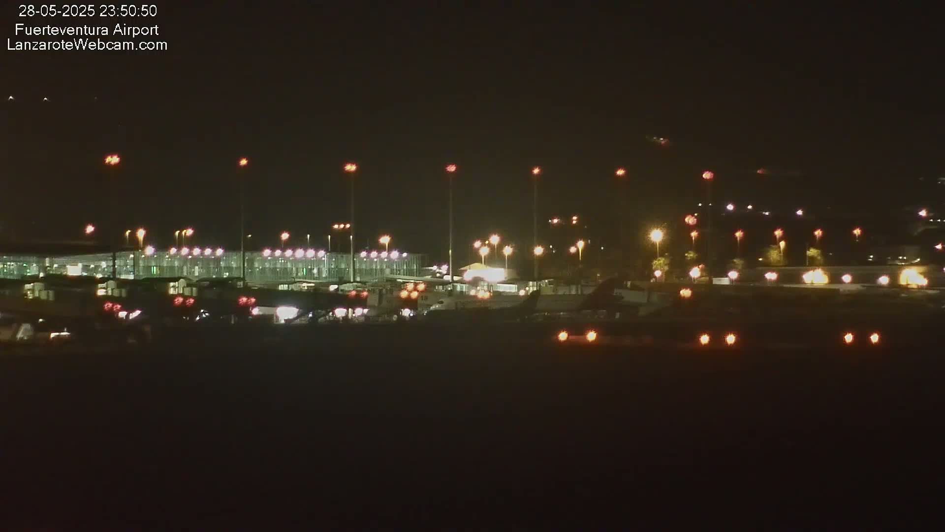 A nighttime view of an airport with illuminated buildings, runways, and aircraft.
