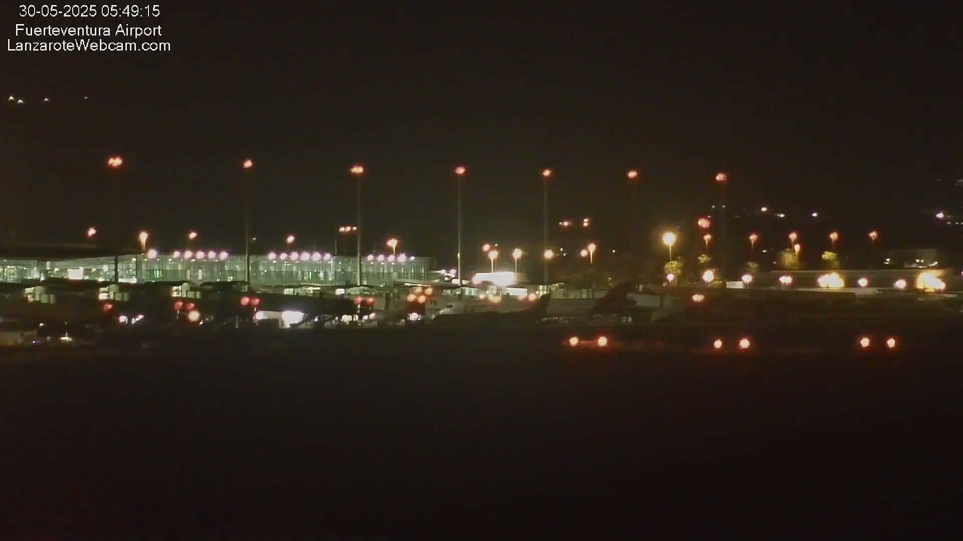 A nighttime view of an airport terminal building illuminated with lights, under a clear, dark sky.