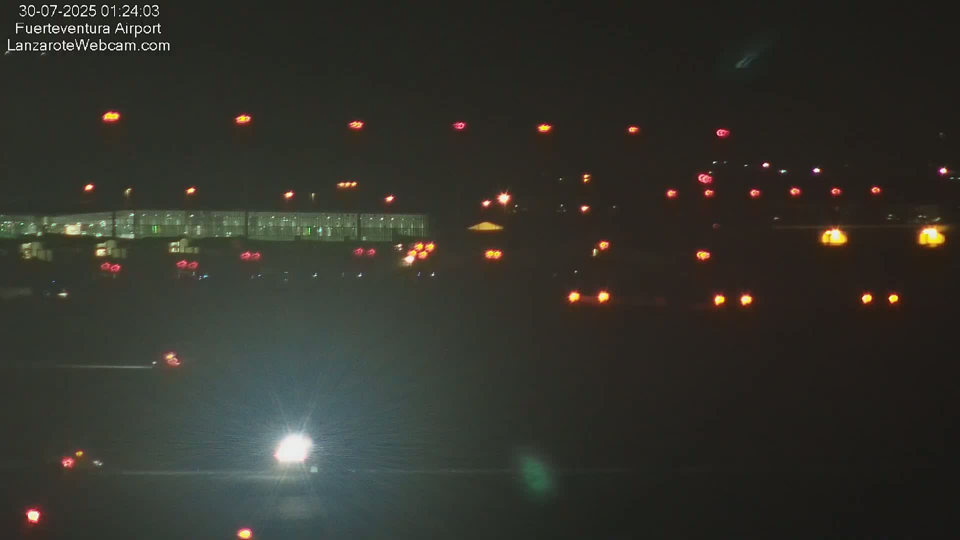 An airplane is parked at a gate of a large airport on a hazy, dusky day.
