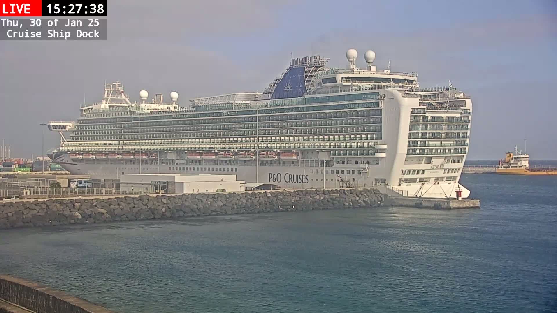 A large cruise ship is docked at a harbor on a partly cloudy day.