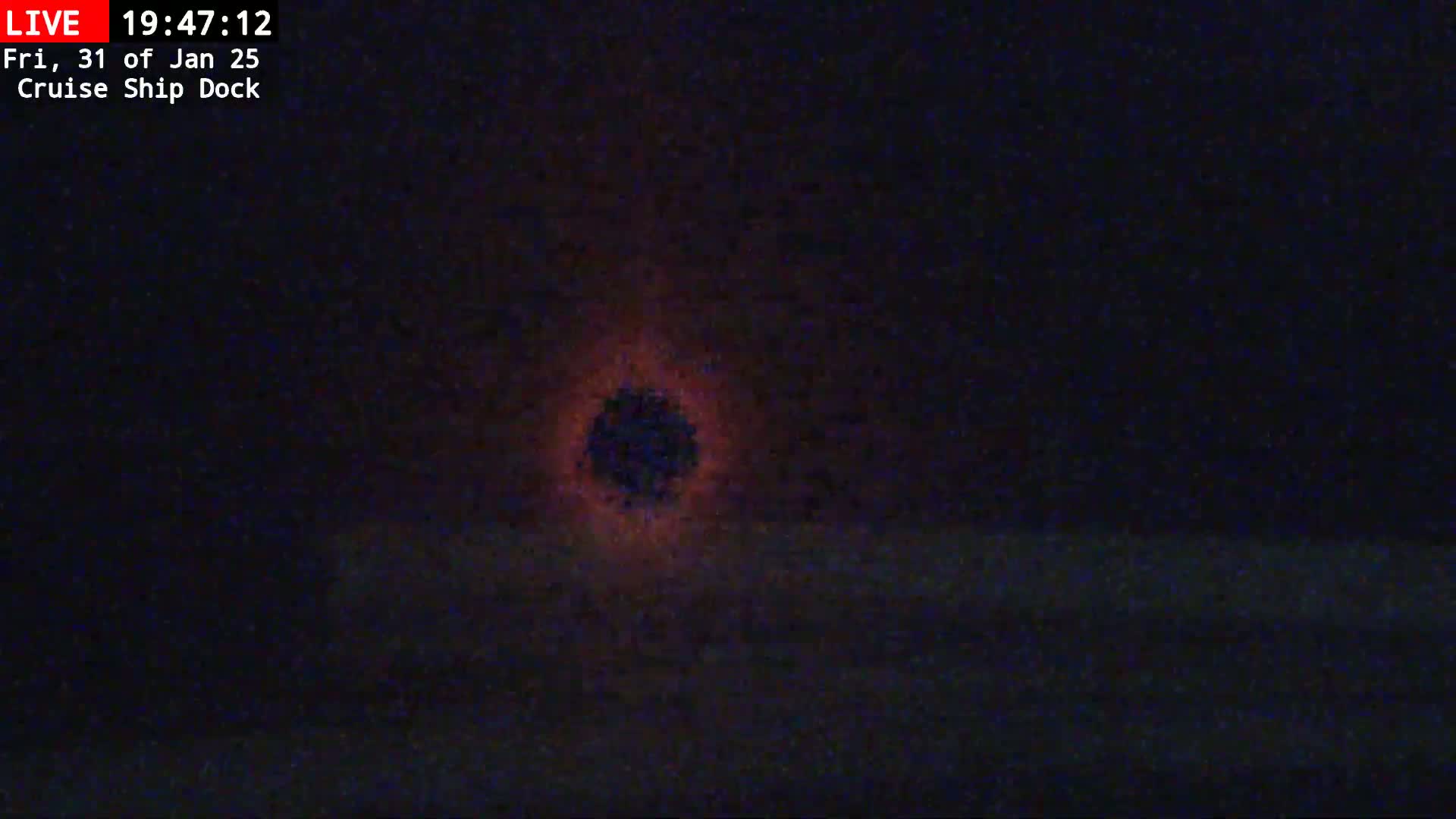 A dark, nighttime scene shows a blurry, reddish-orange glow in the center of the frame.