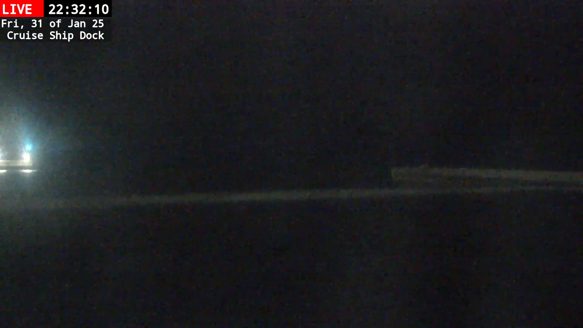 A dark nighttime scene shows a dimly lit dock area with a faint light source in the distance.