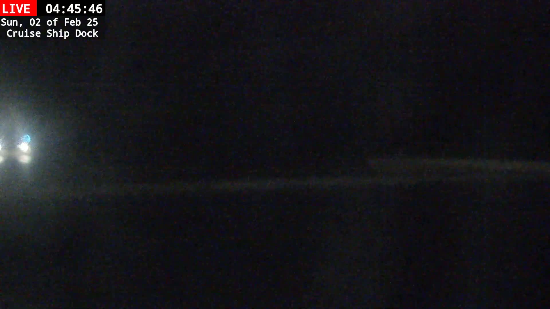 A dark nighttime scene shows a blurry, indistinct horizon line with faint light sources in the distance.