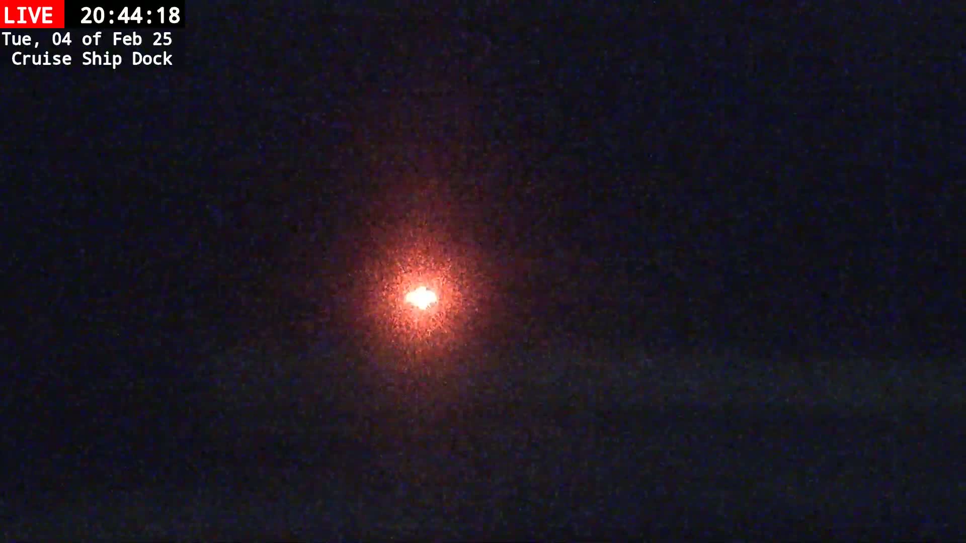 A bright, reddish-orange light is visible in the center of a dark, nighttime sky.