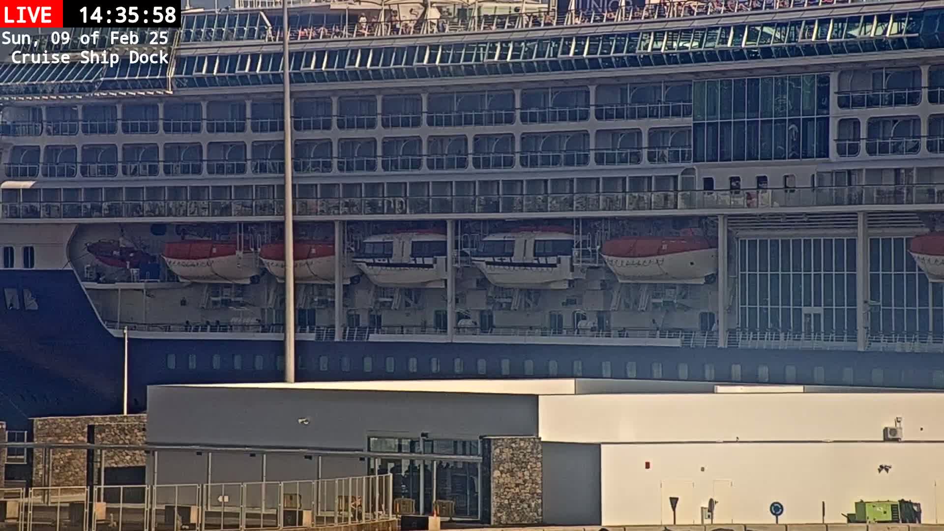 A large cruise ship is docked at a port on a sunny day.