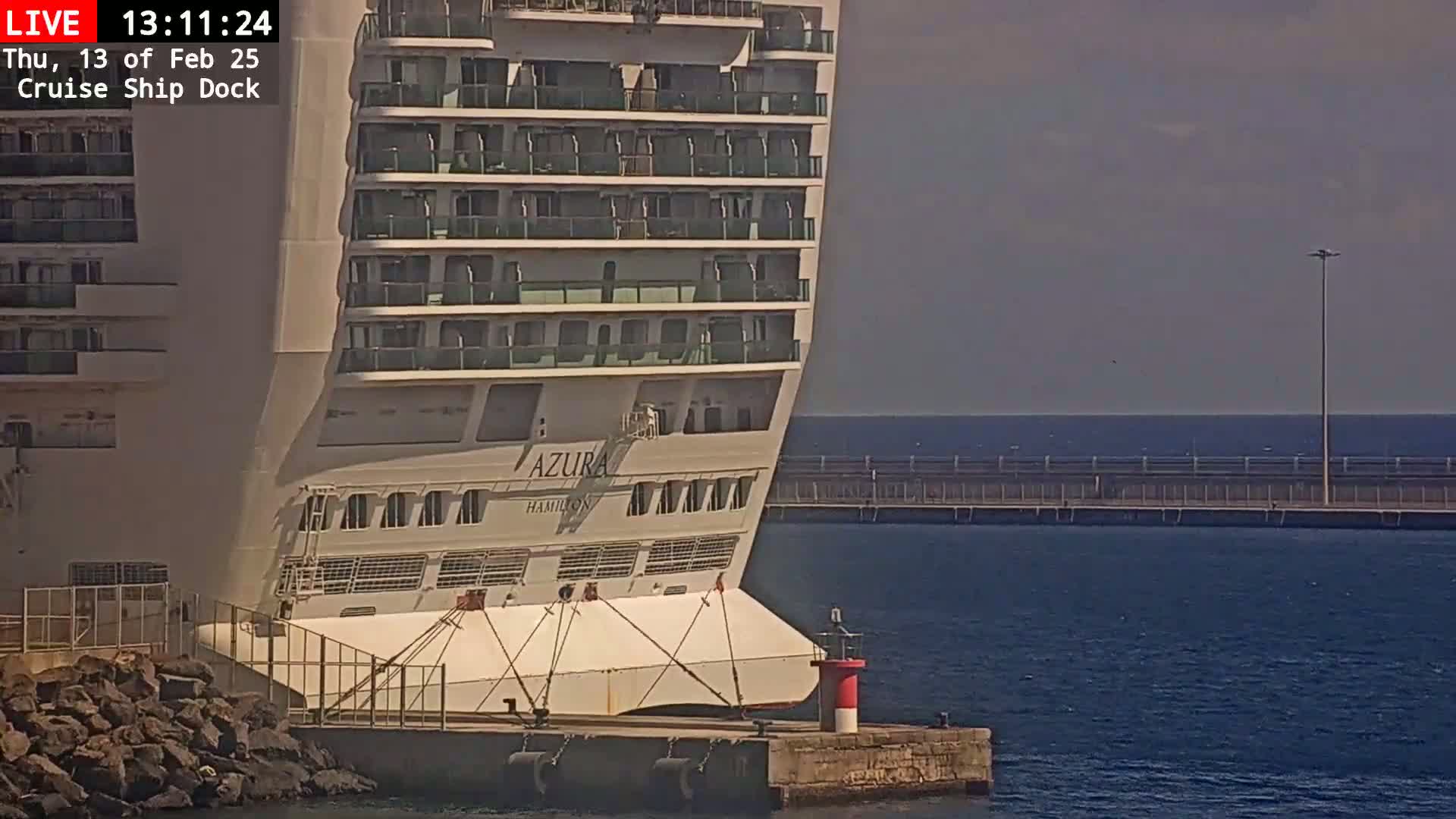 A large cruise ship is docked at a pier on a partly cloudy day.