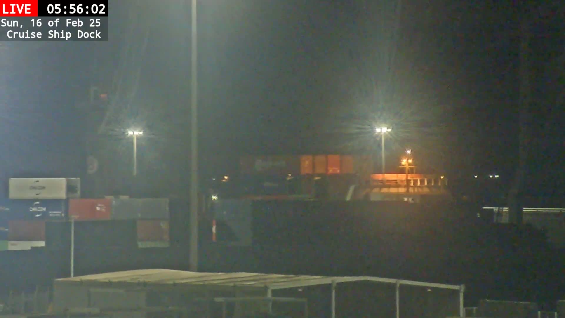 A large ship is docked at night under hazy, dimly lit conditions.
