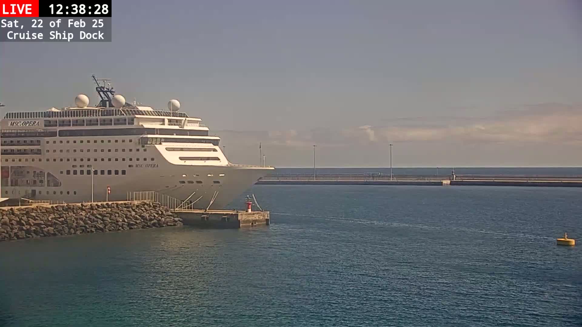 A large cruise ship is docked at a port on a partly cloudy day.