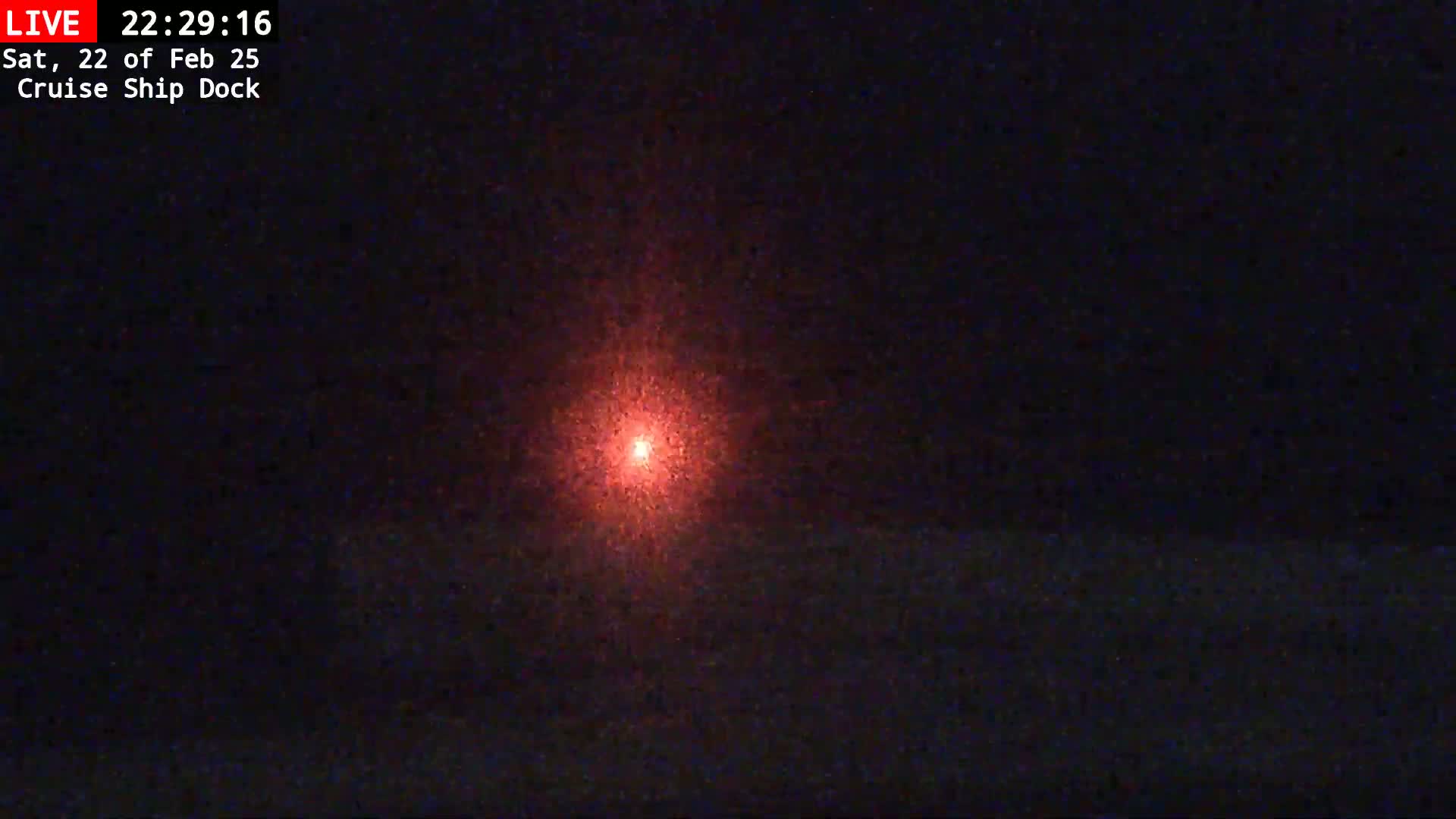 A bright red light is visible in the center of a dark nighttime scene.