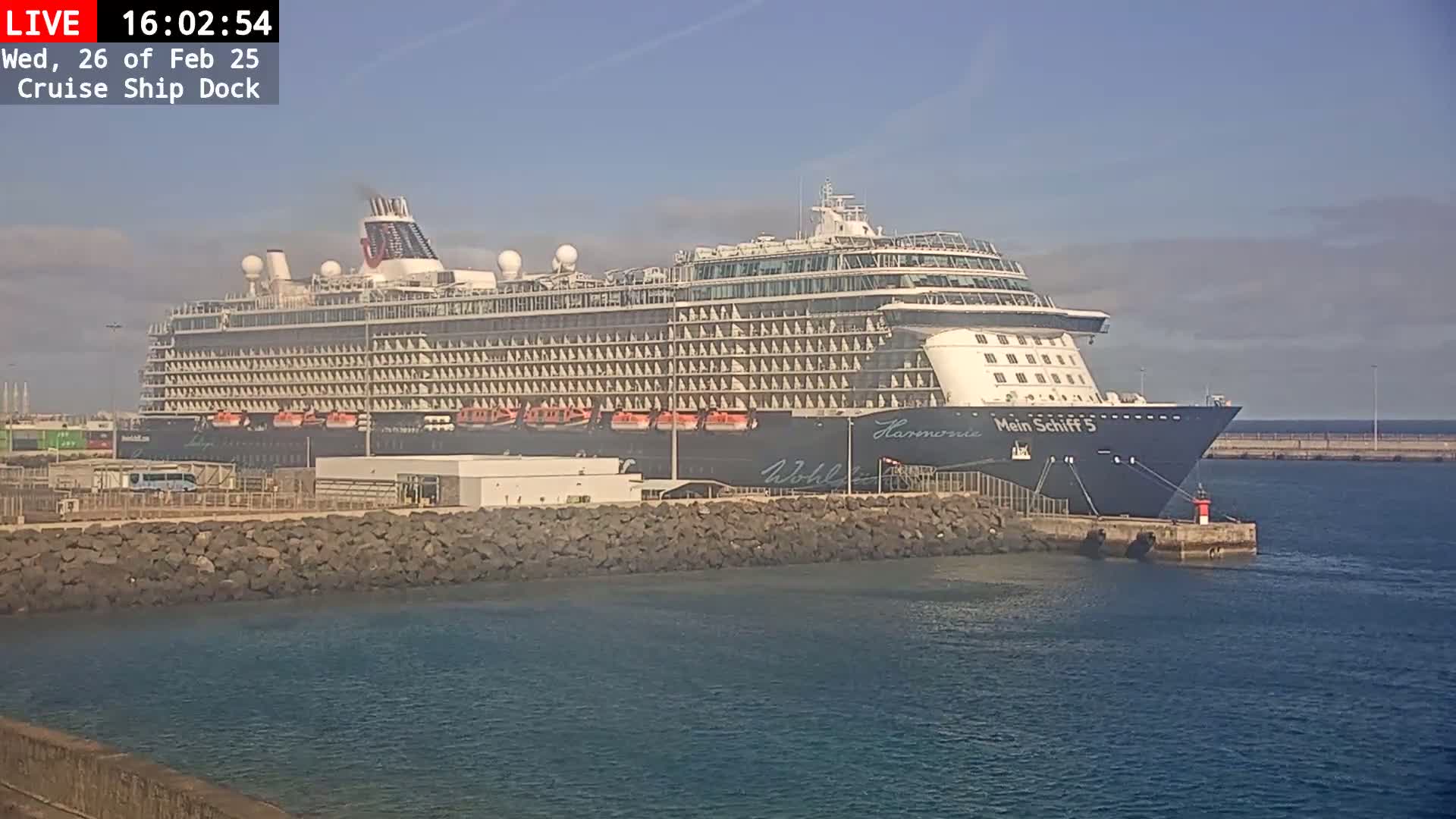 A large cruise ship is docked at a port on a sunny day.