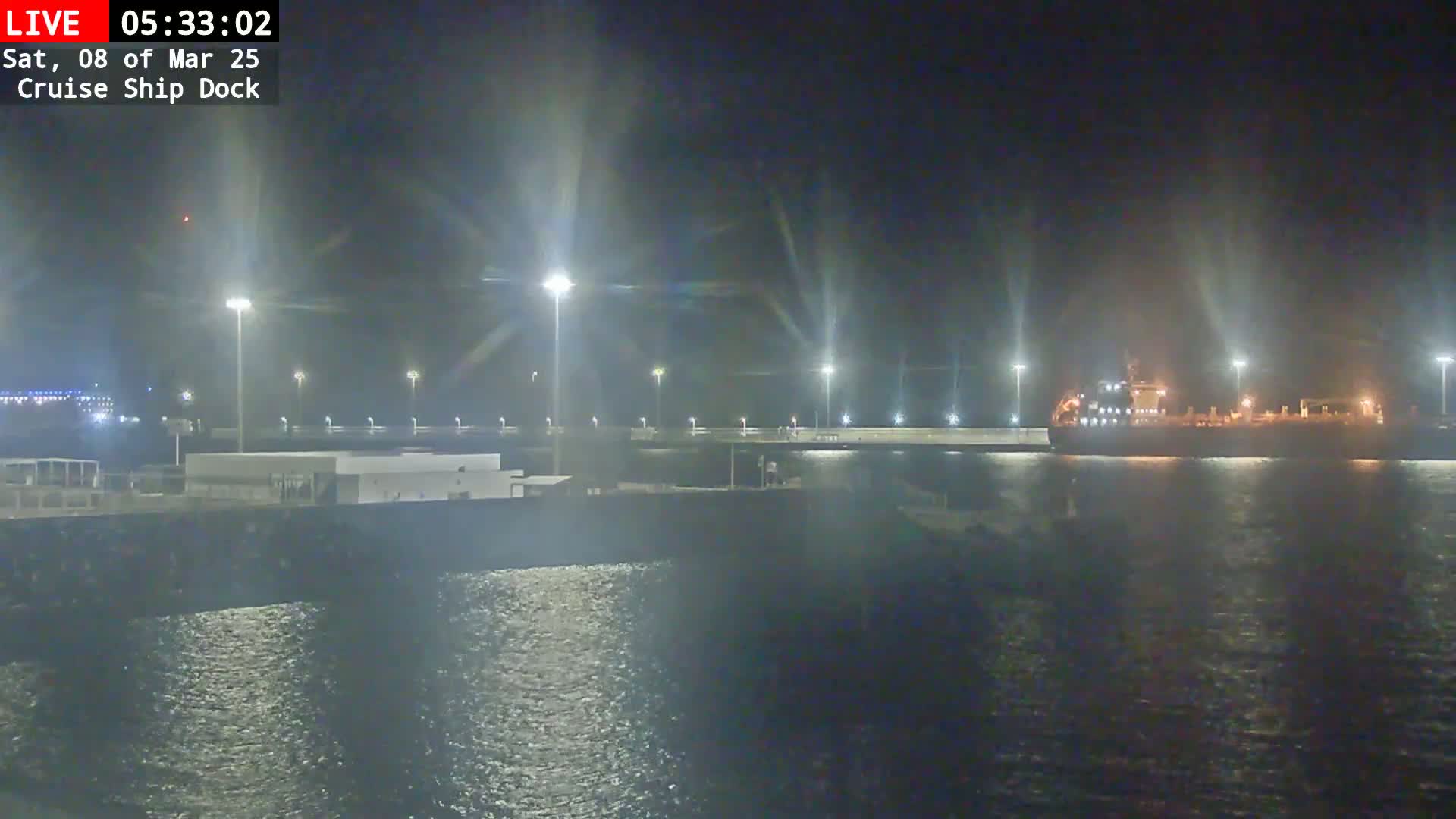 A large ship is docked at a brightly lit port at night.