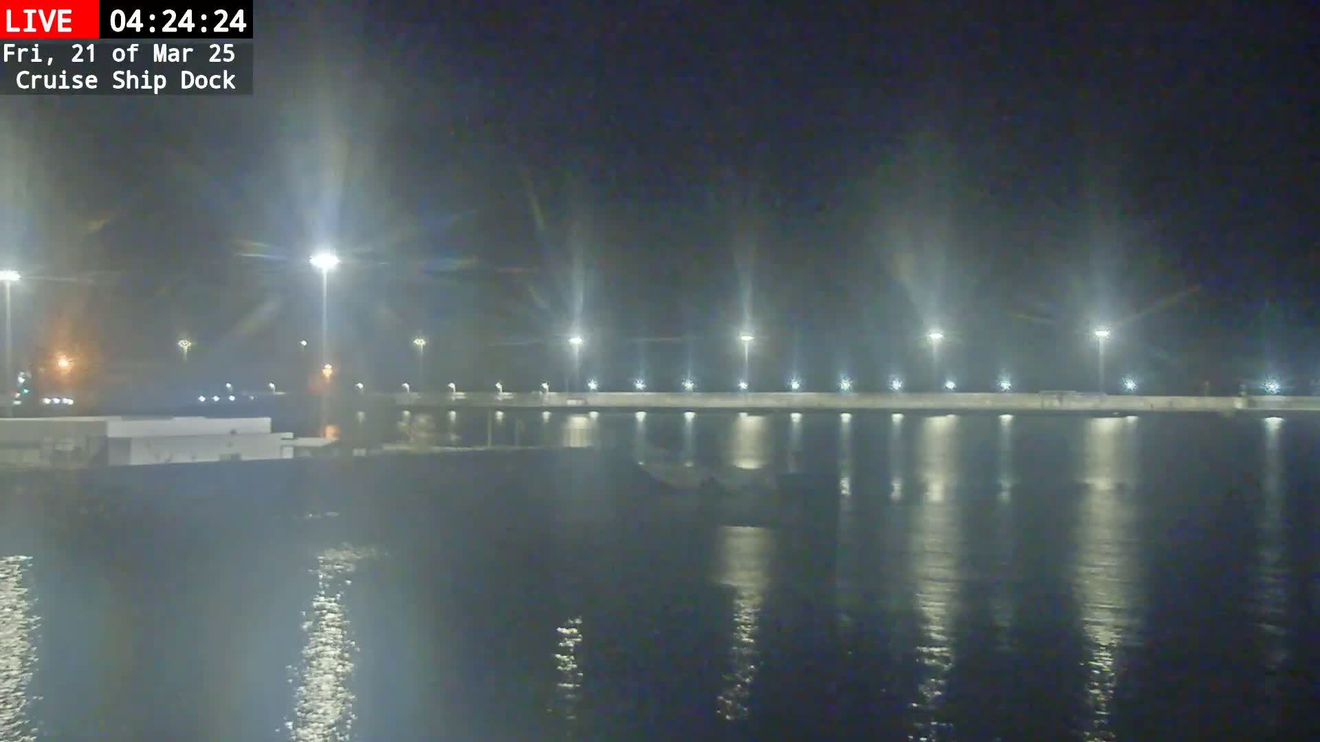 A nighttime view of a calm body of water reflecting the lights of a cruise ship dock.