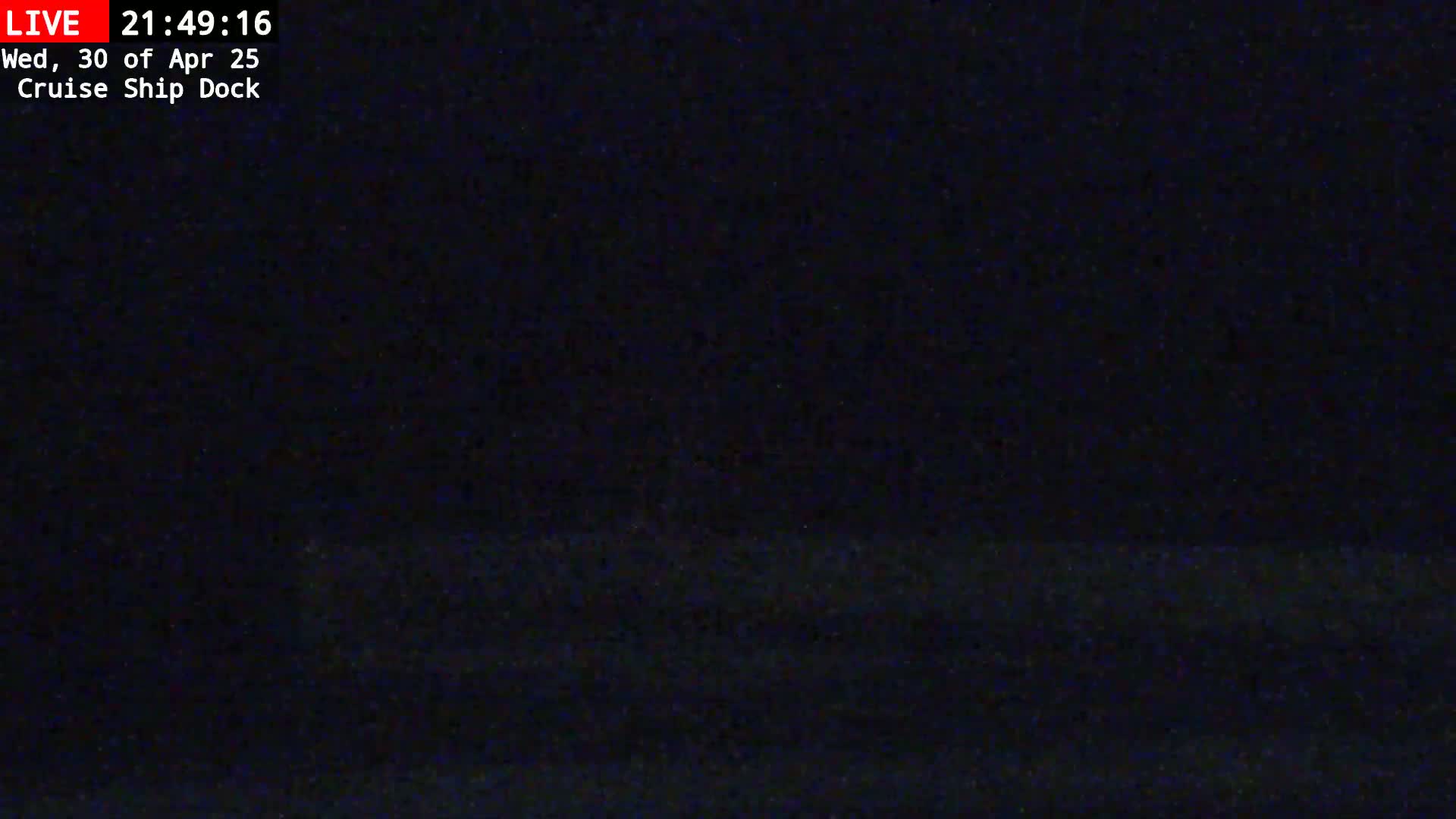 A dark, nighttime view of a cruise ship dock.