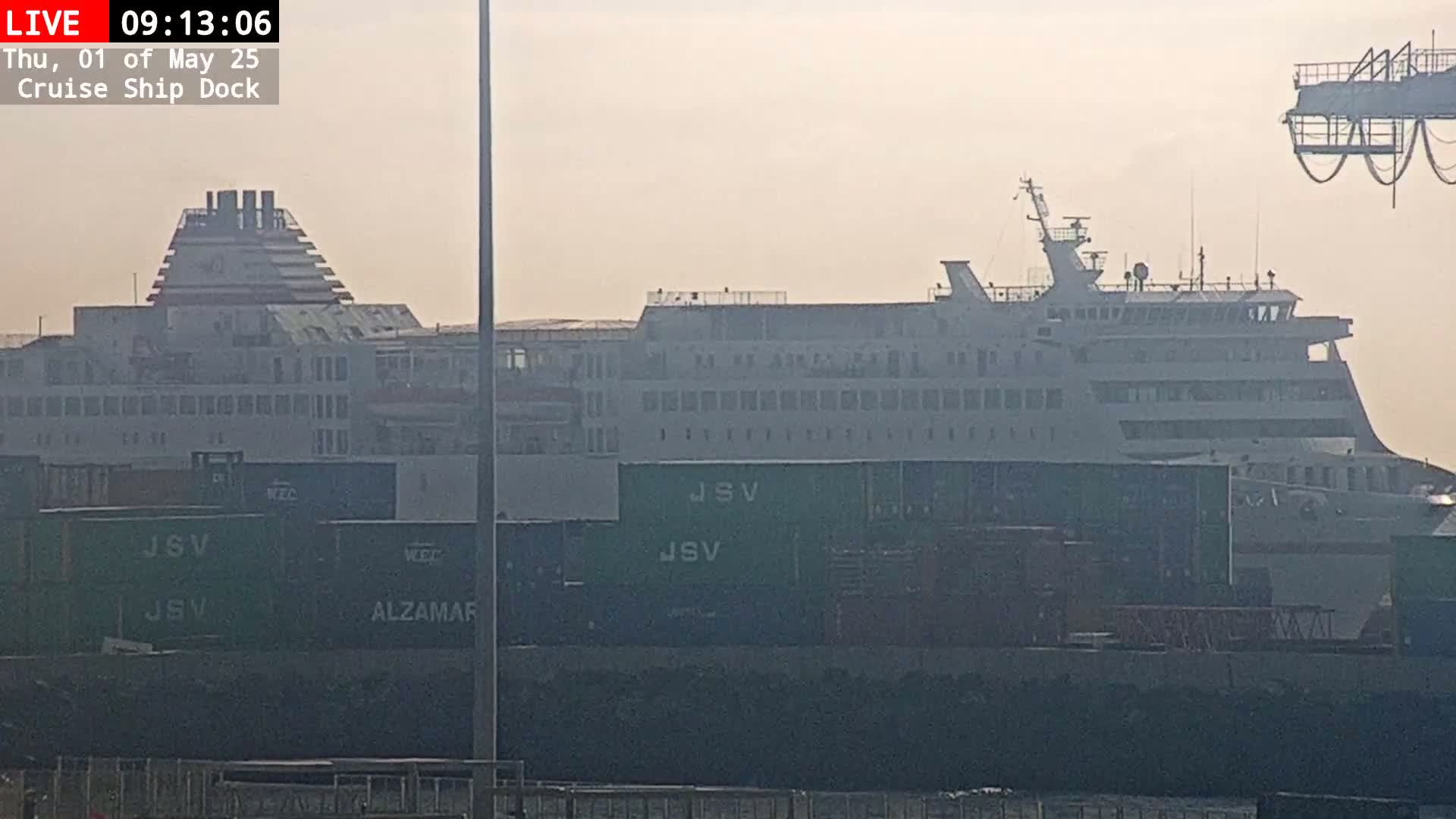 A large cruise ship sits at a dock on a hazy day.