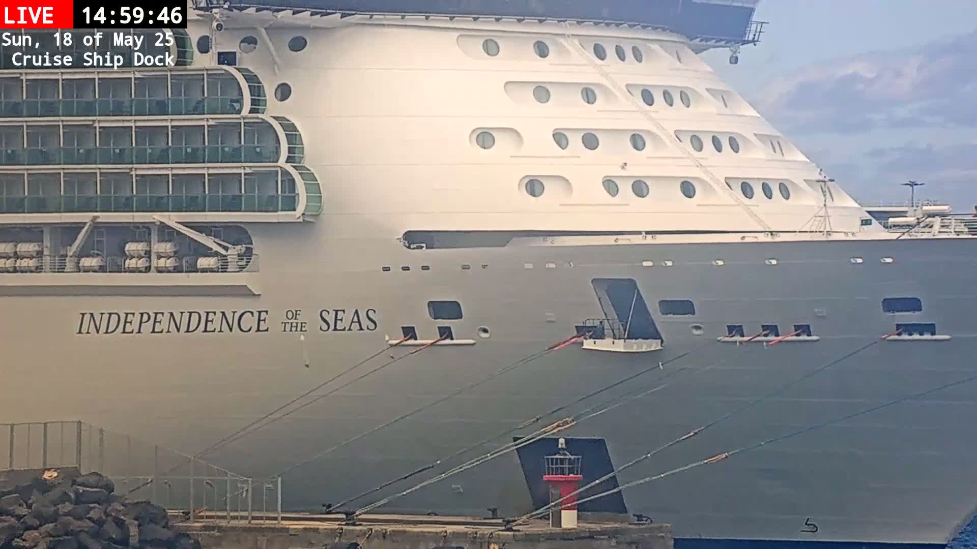 A large cruise ship, the Independence of the Seas, is docked, under mostly cloudy skies.