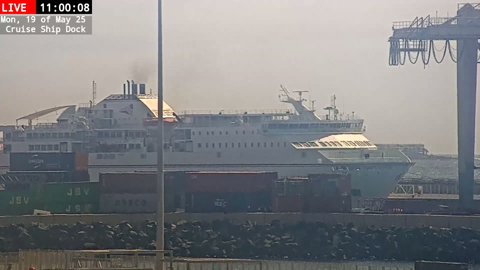 A large ferry is docked at a port on a hazy day.