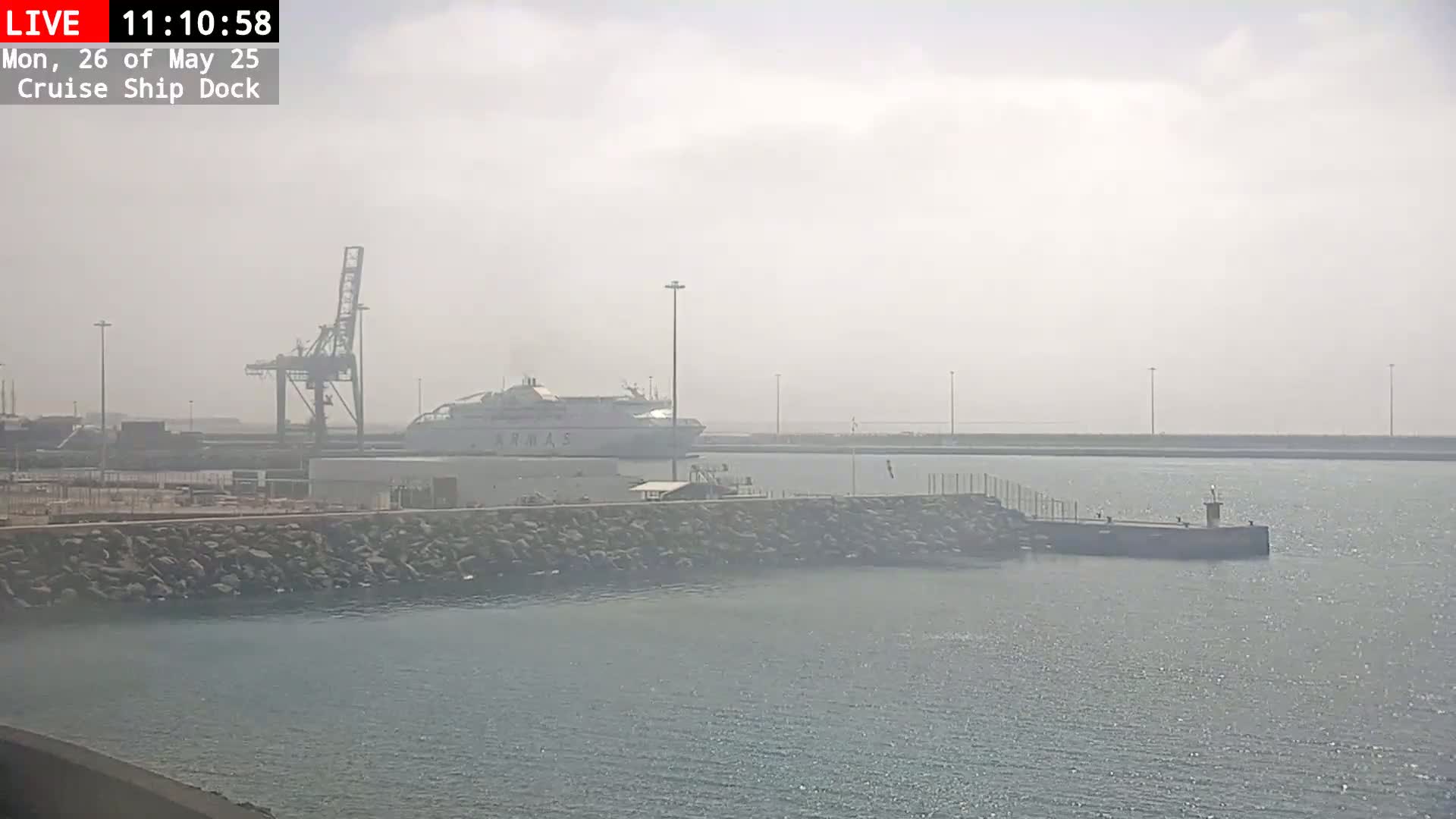 A large ferry is docked at a port on a hazy day.