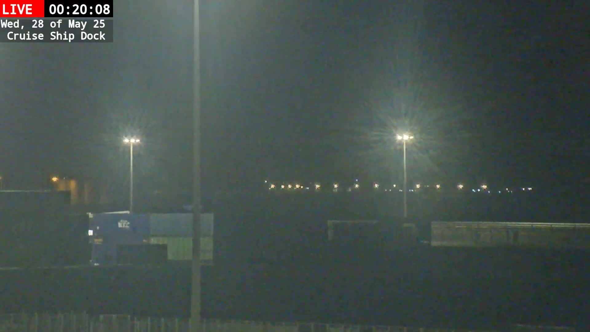 A nighttime view of a dimly lit cruise ship dock with several tall lights illuminating a mostly dark area.