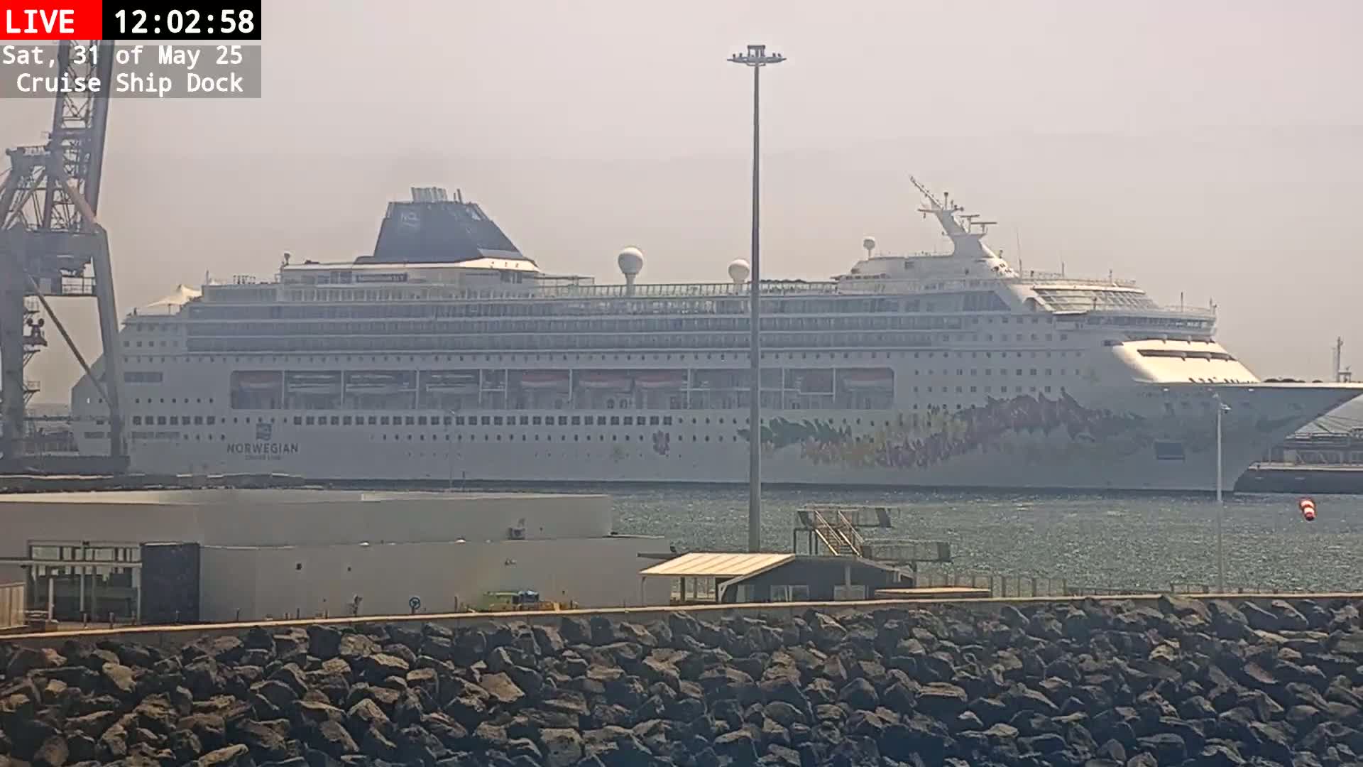 A large cruise ship is docked at a pier on a hazy day.