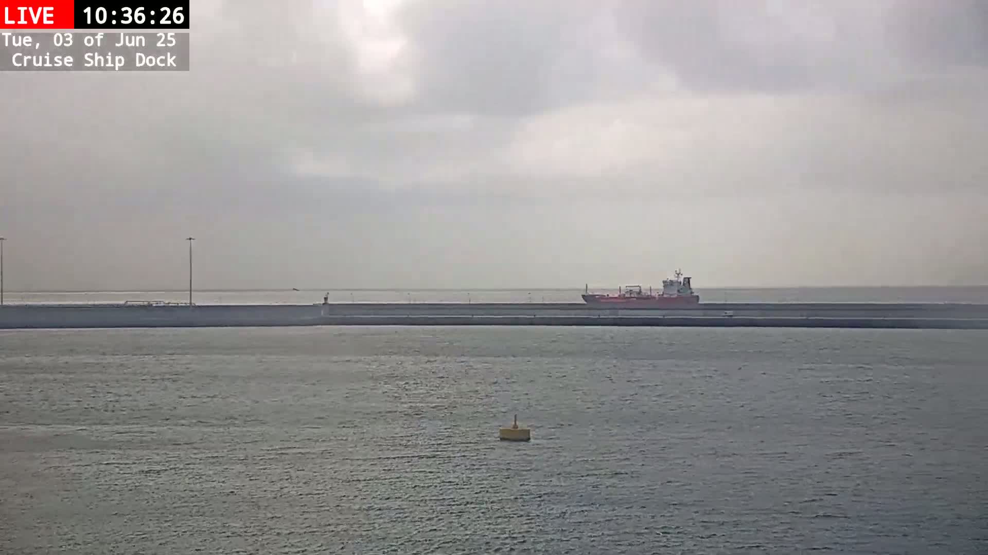 A large ship is docked at a cruise ship terminal on an overcast day.