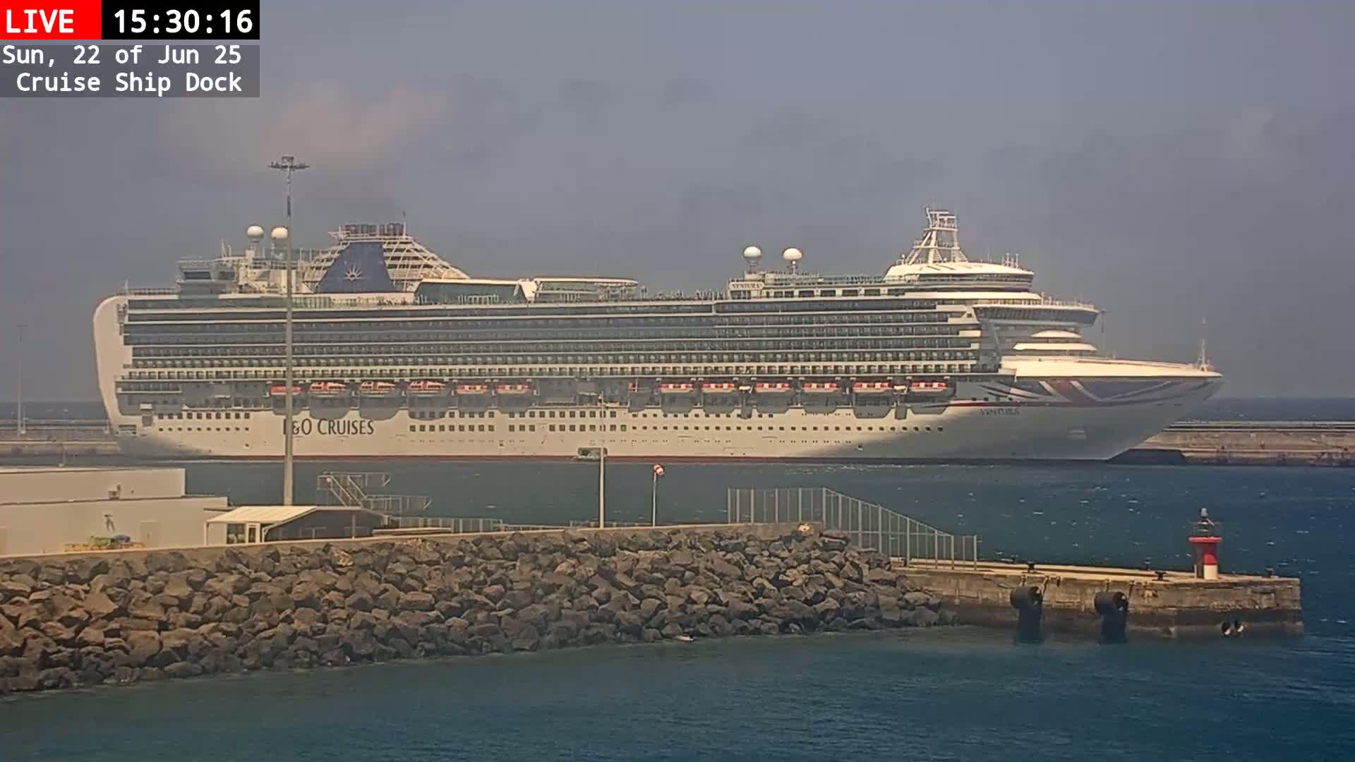 A large cruise ship is docked at a port on a hazy day.