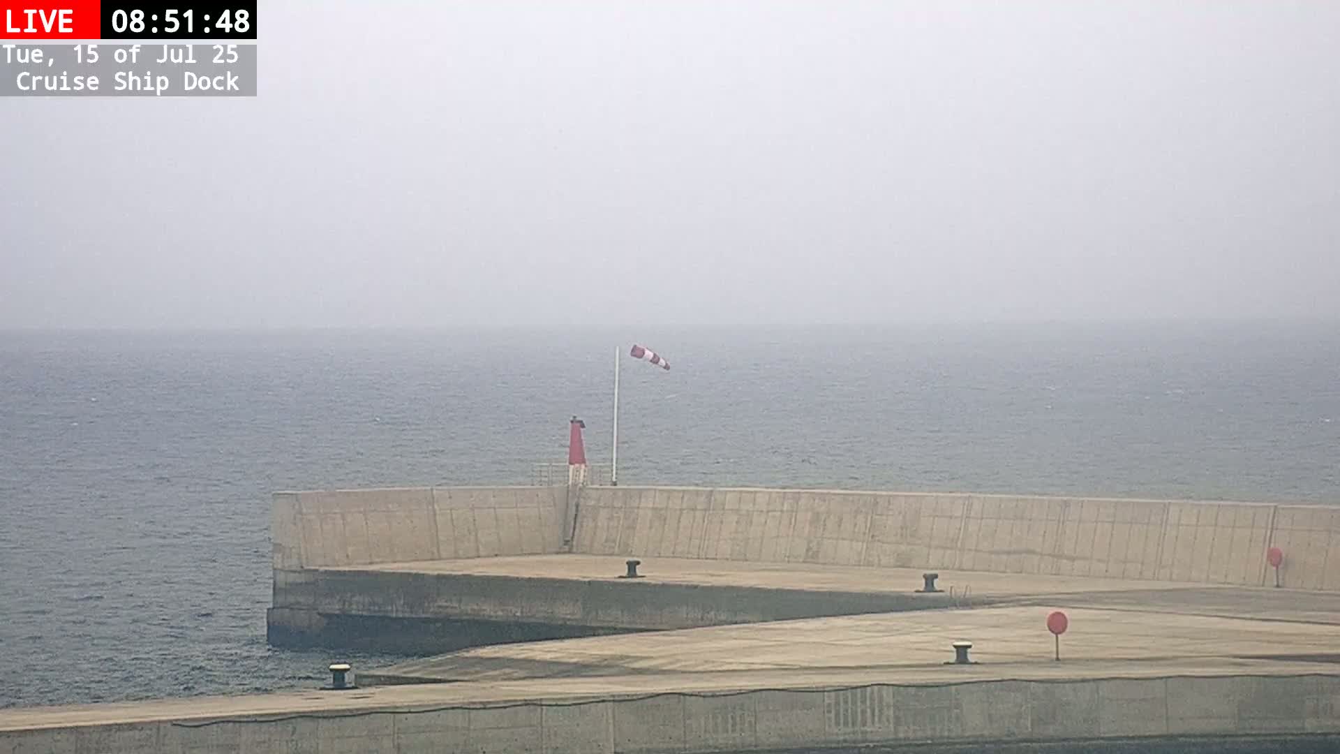 A hazy view of a cruise ship dock with a windsock indicating the wind direction.