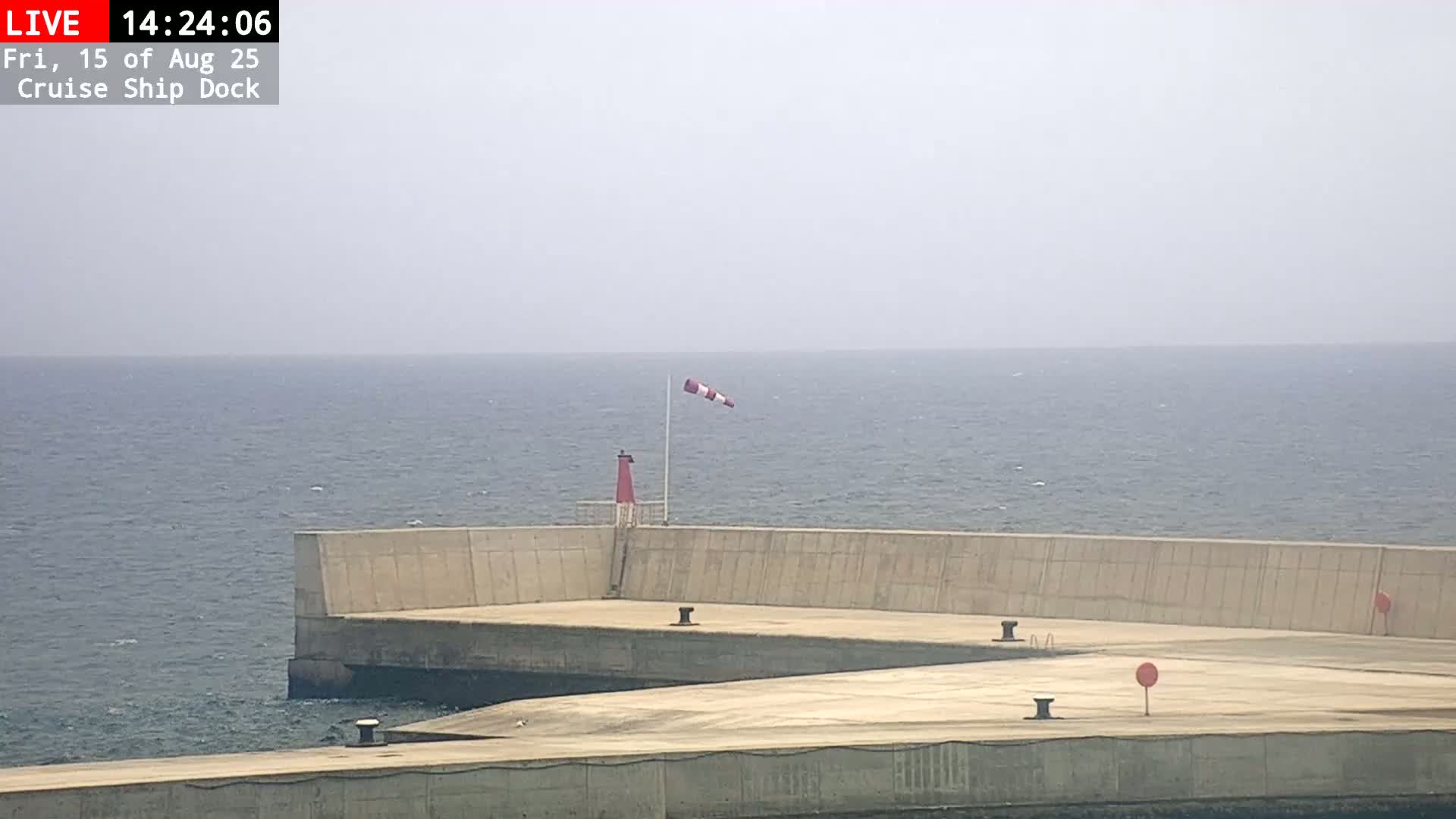 A large sailing ship is docked at a harbor on a hazy day.