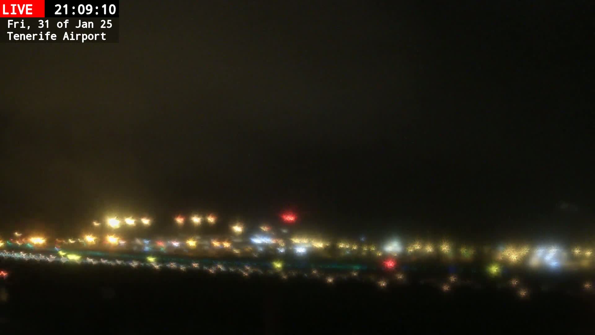 A hazy, dark night scene shows a blurred line of multicolored lights at a distance.