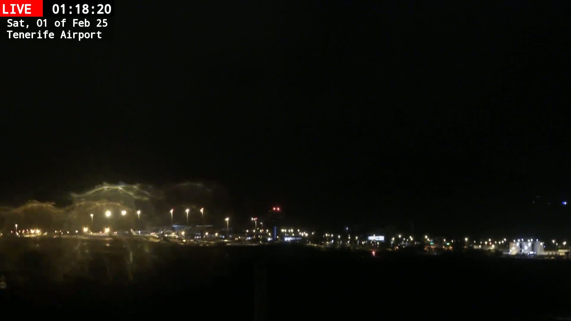 A nighttime view of an airport with low clouds or fog illuminated by runway lights.