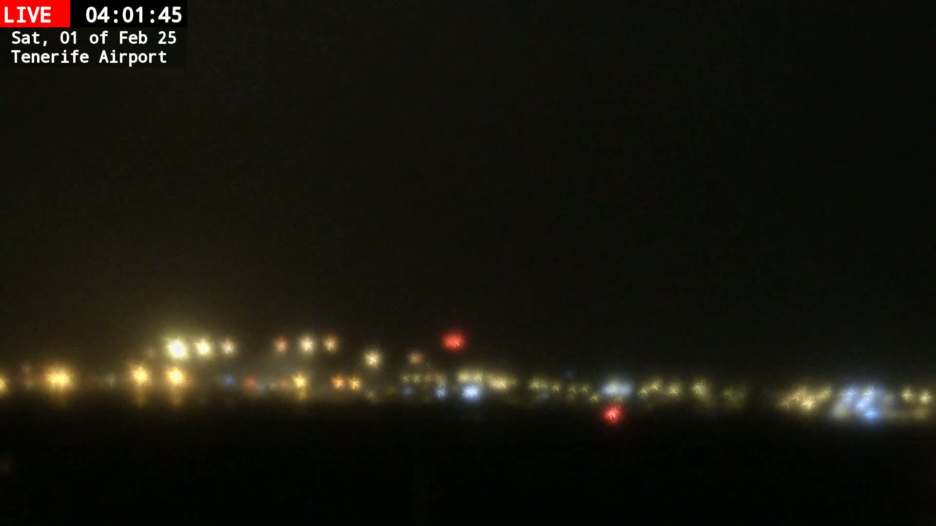 A hazy, nighttime view of a distant line of lights, possibly an airport, under foggy conditions.