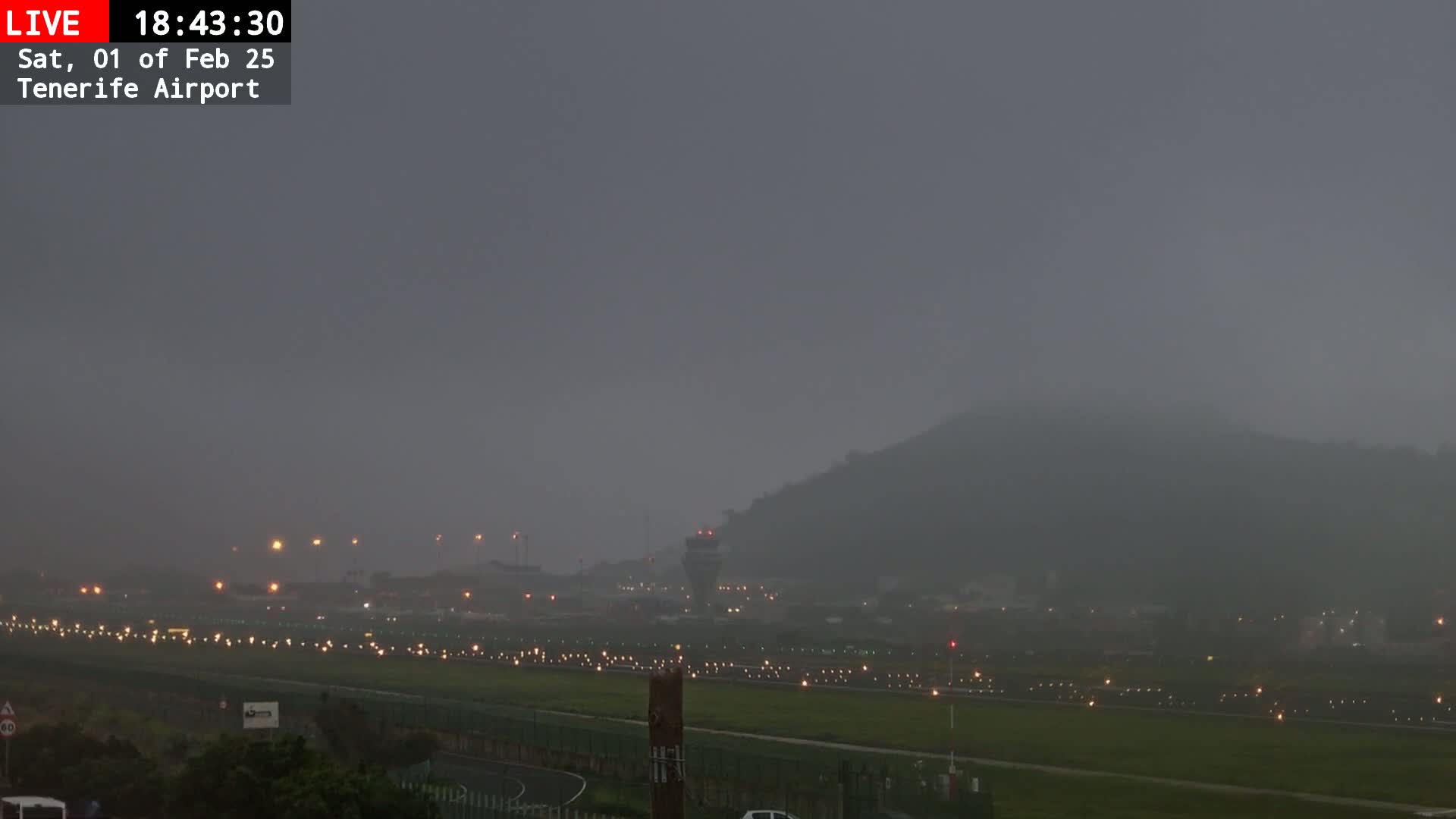 A foggy, dimly lit airport runway extends toward a hill shrouded in mist.