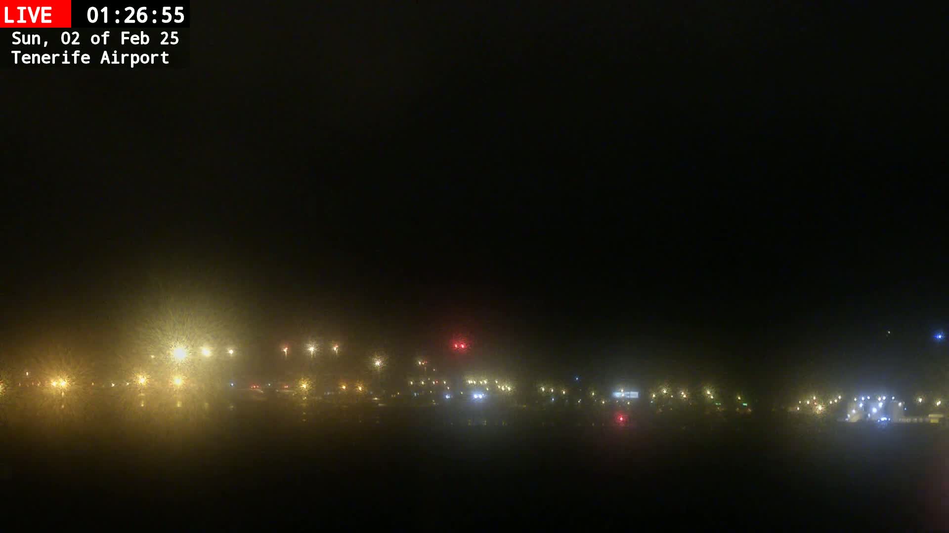 A nighttime view of a foggy airport with numerous lights visible in the distance.