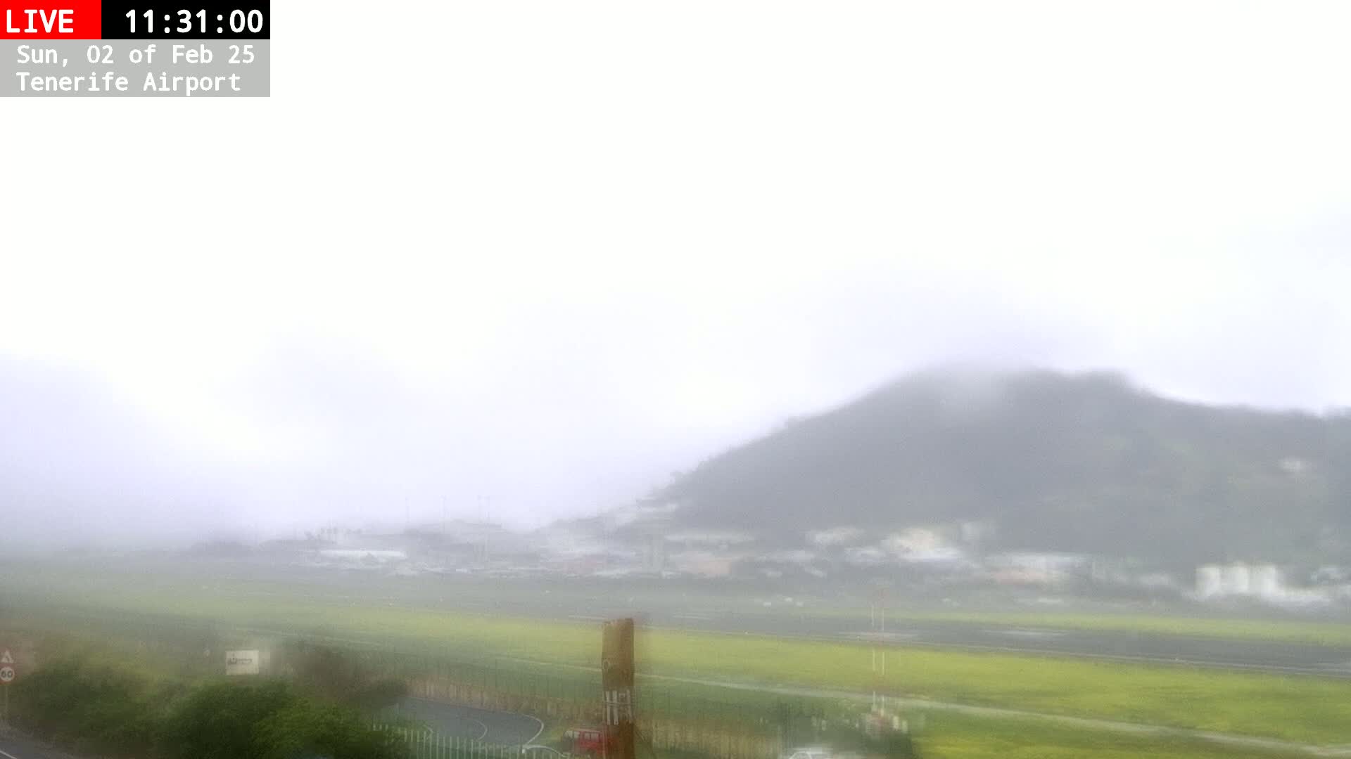 A foggy view of an airport runway and a hillside in the background.